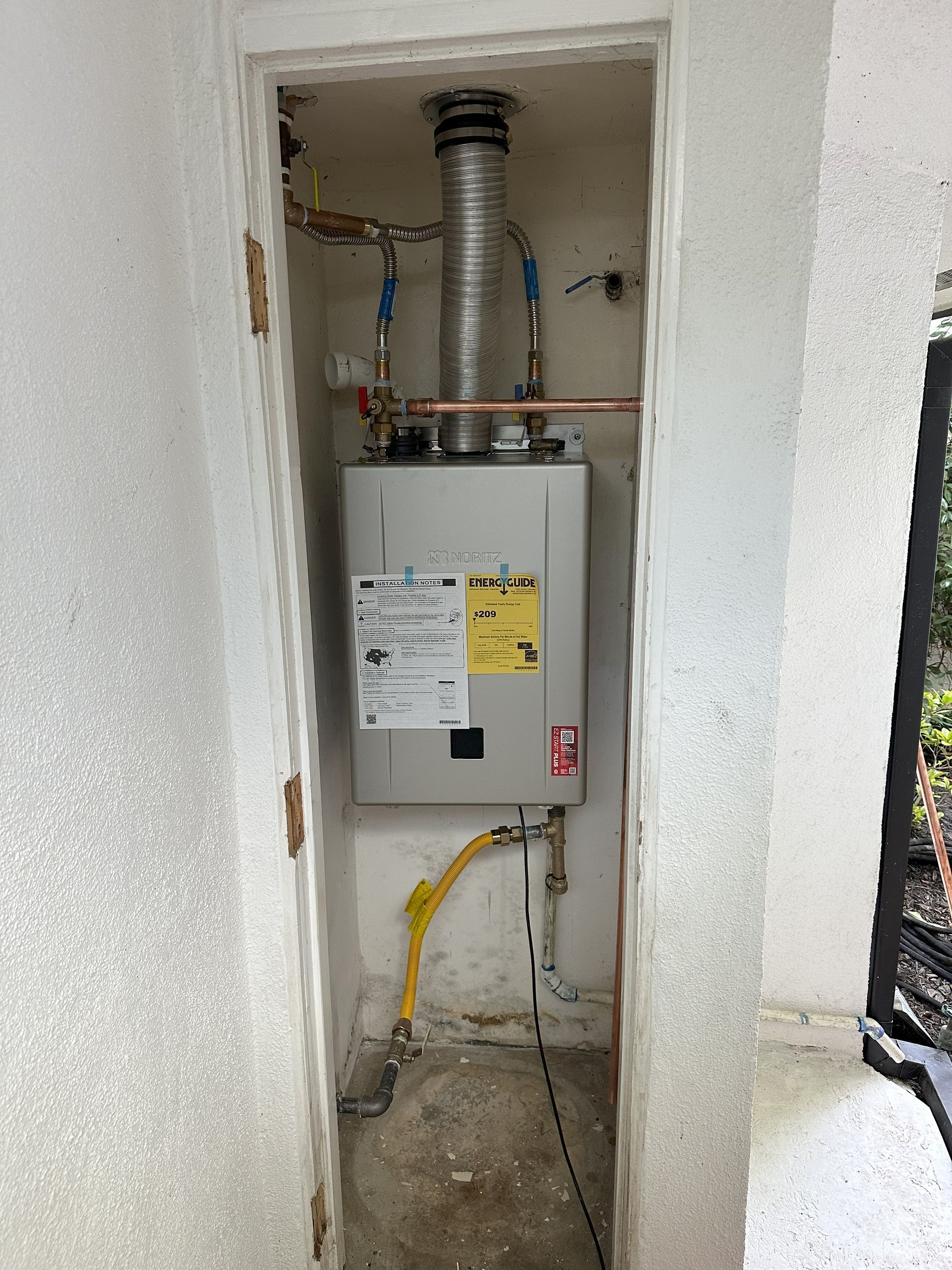 A water heater is installed in a closet next to a door.