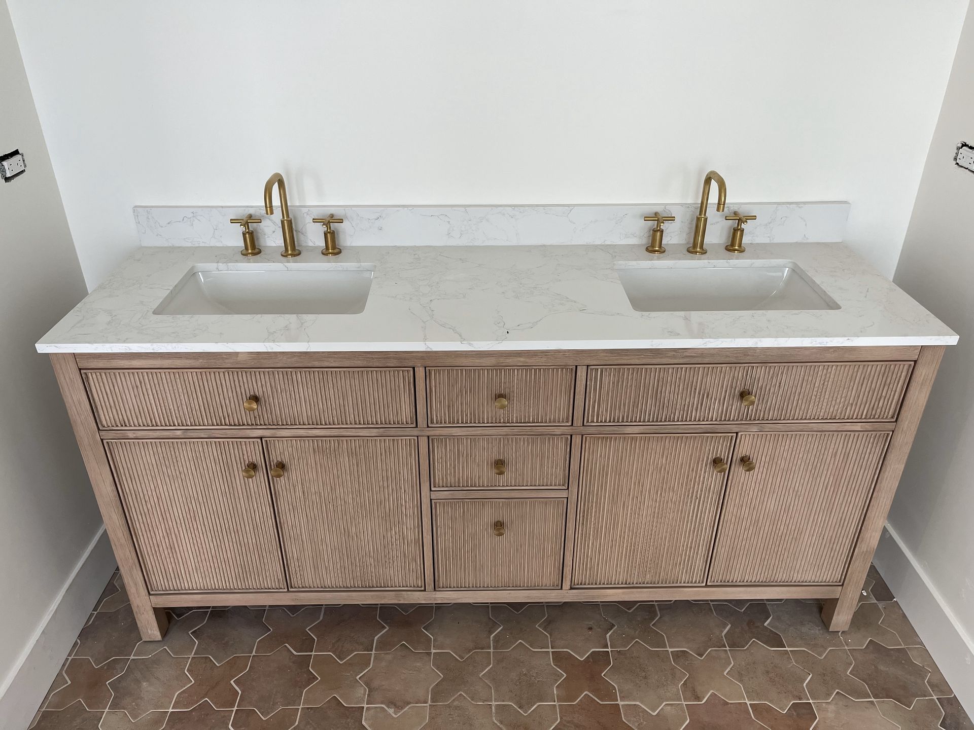 A bathroom vanity with two sinks and two faucets