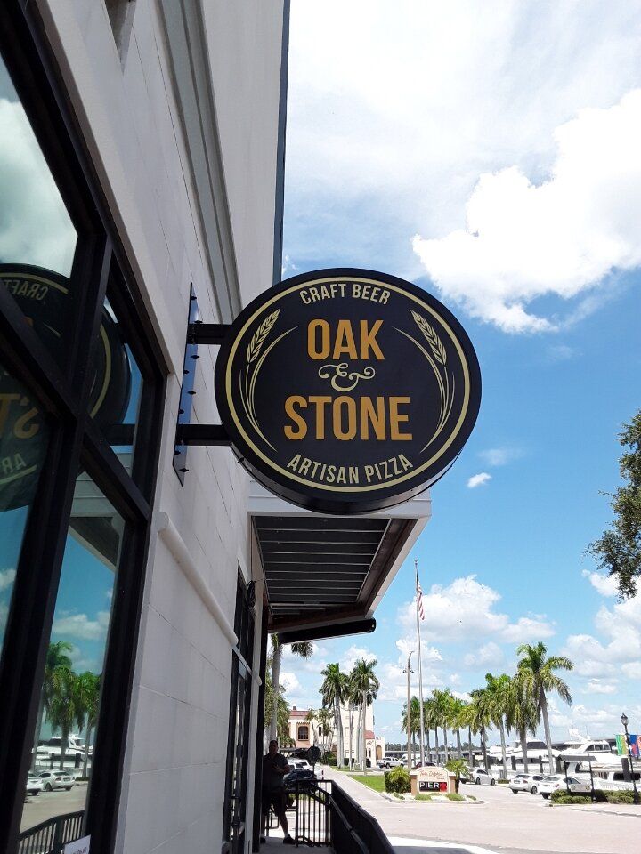 A sign on the side of a building that says Oak & Stone - Craft Beer / Artisan Pizza in Bradenton Florida