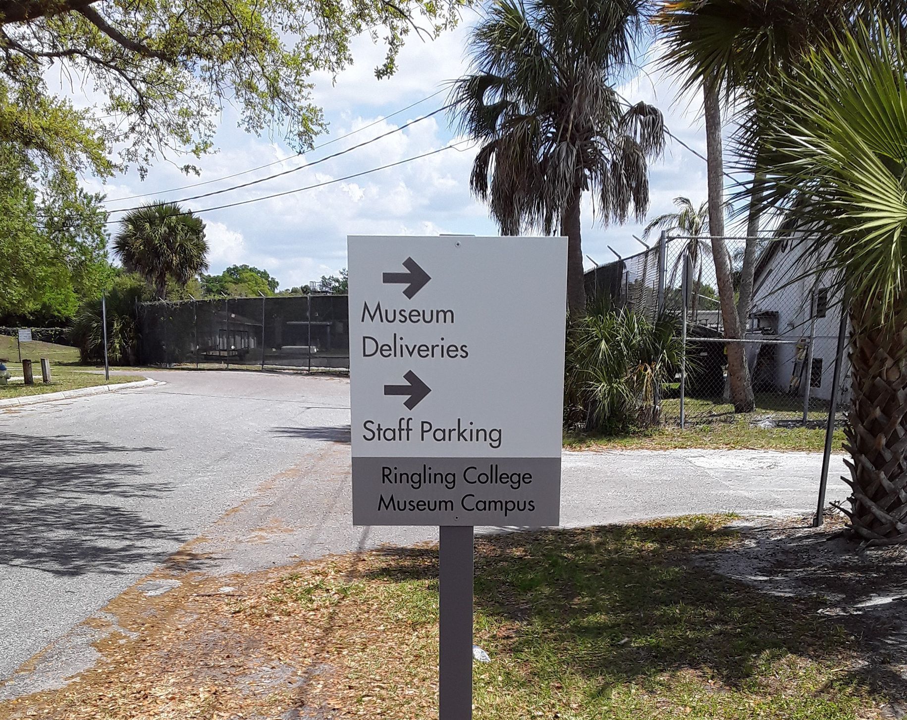 Signpost with arrows for Museum Deliveries and Staff Parking at Ringling College, St. Louis Campus.