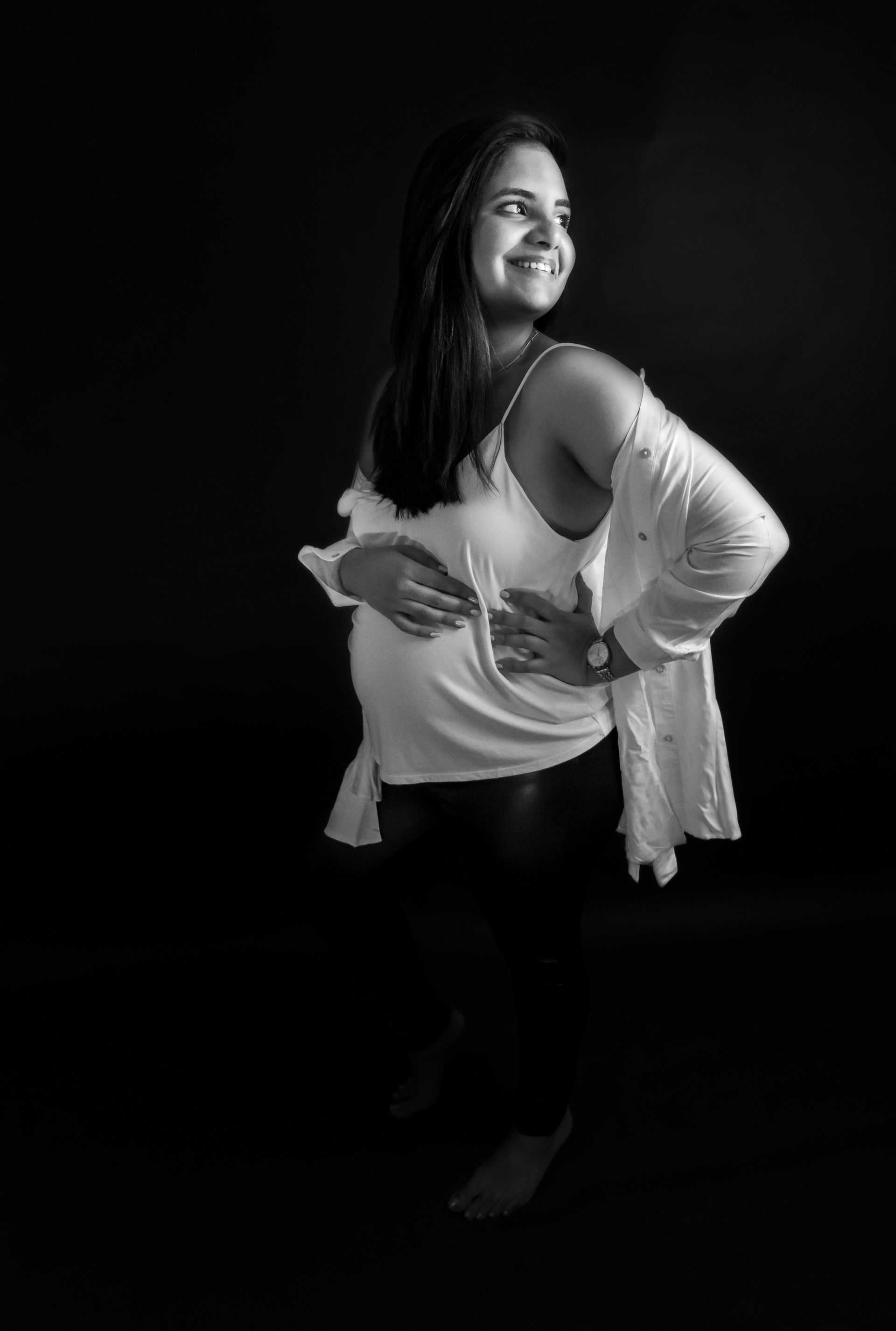 A black and white photo of a pregnant woman holding her belly.