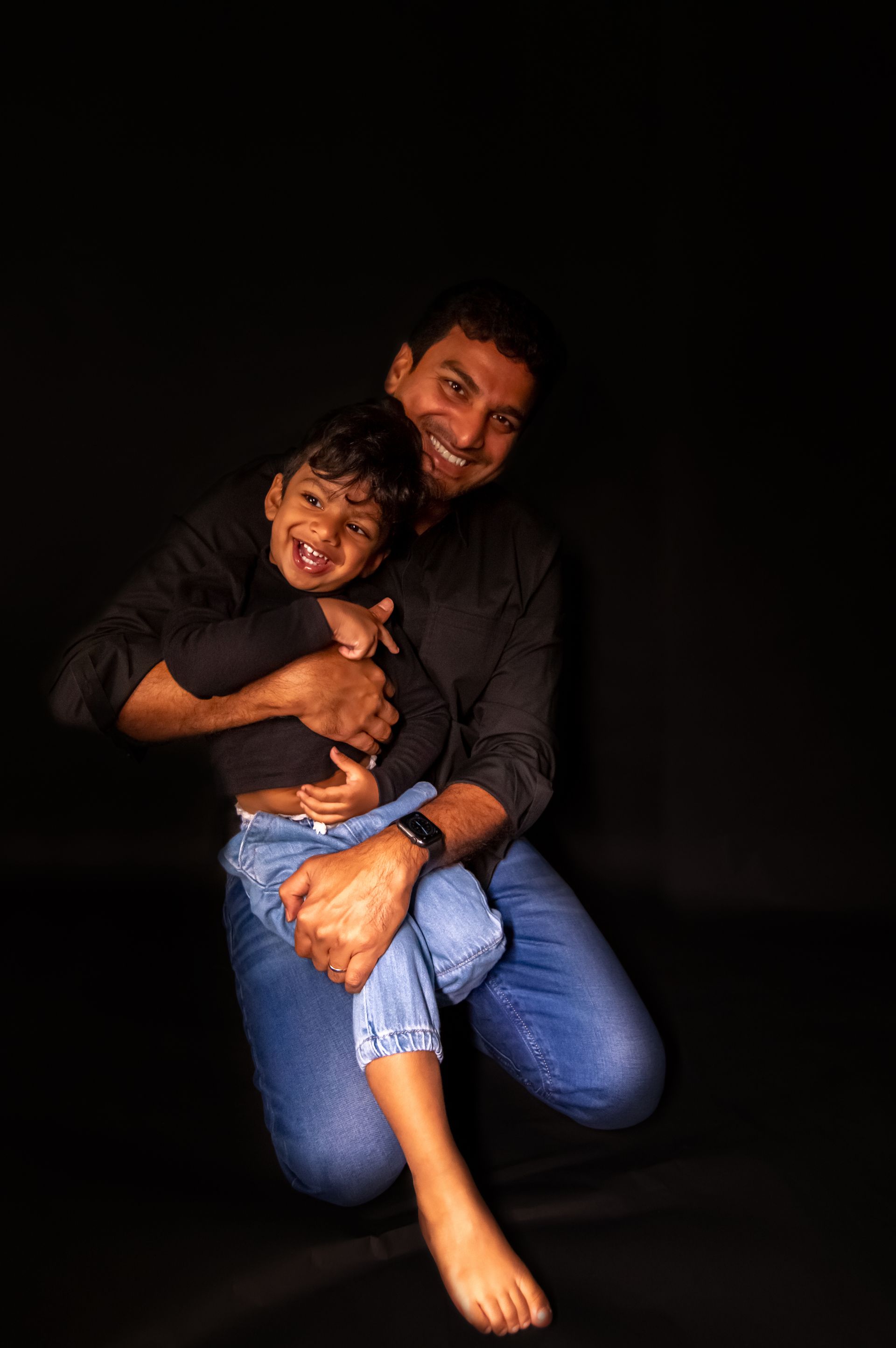A man is kneeling down holding a little boy in his arms.