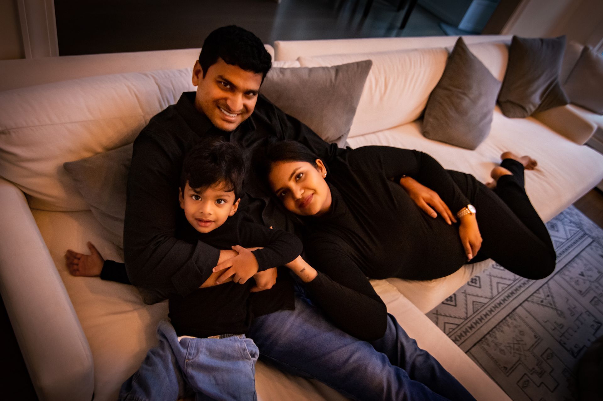 A man , woman and child are laying on a couch.