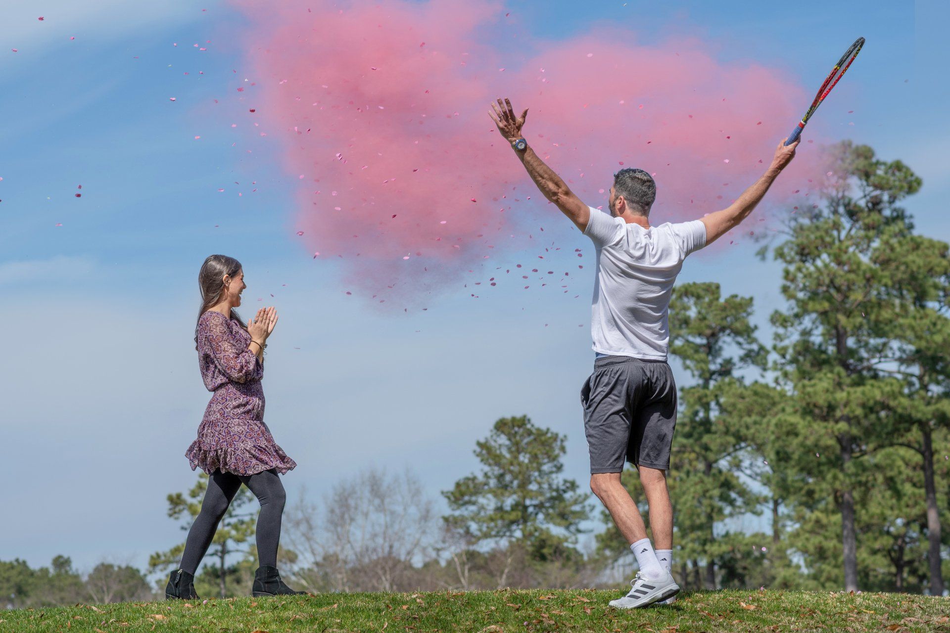 A man and a woman are throwing pink powder in the air.