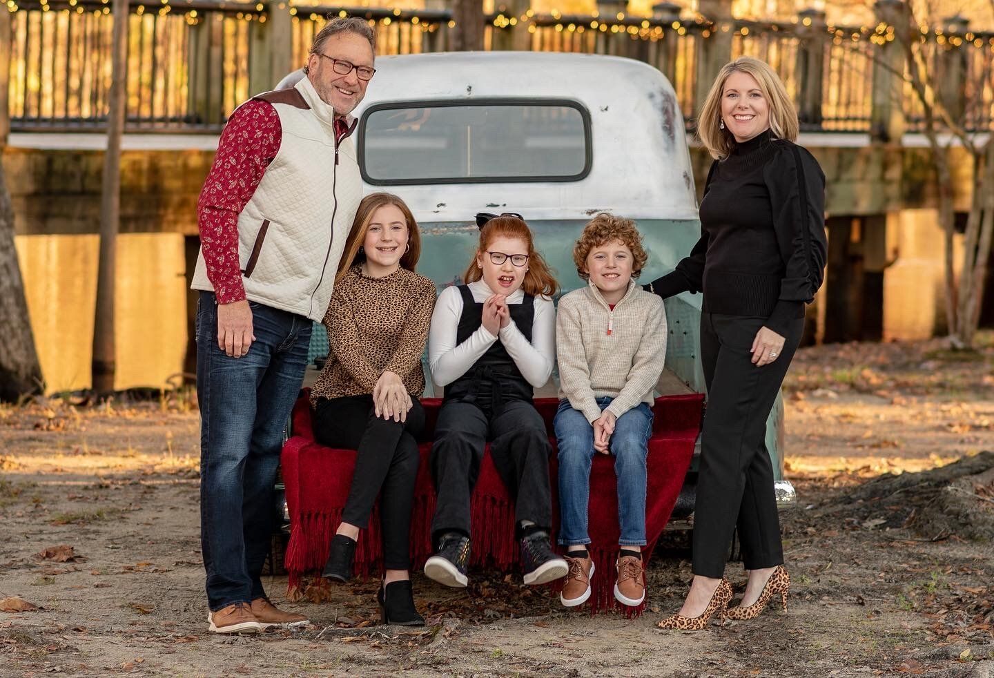 A family is posing for a picture in front of a truck.