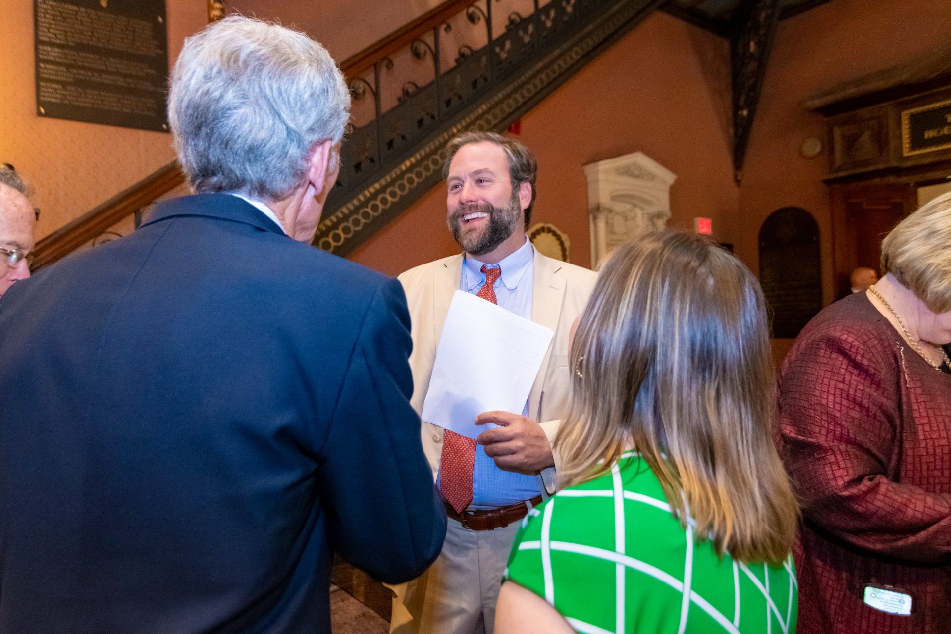 A group of people are standing around a man holding a piece of paper.