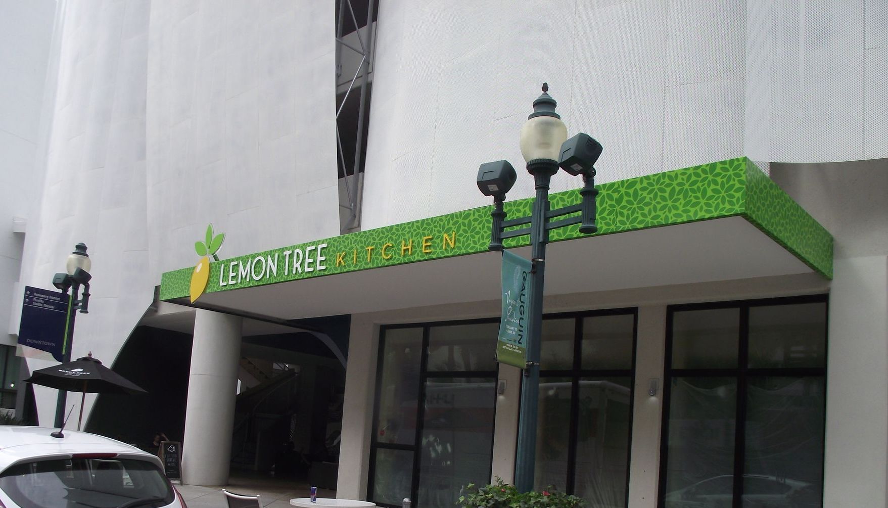 Lemon Tree Kitchen restaurant entrance with green wrapped awning sign, cut out lemon and letters on white building in SRQ.