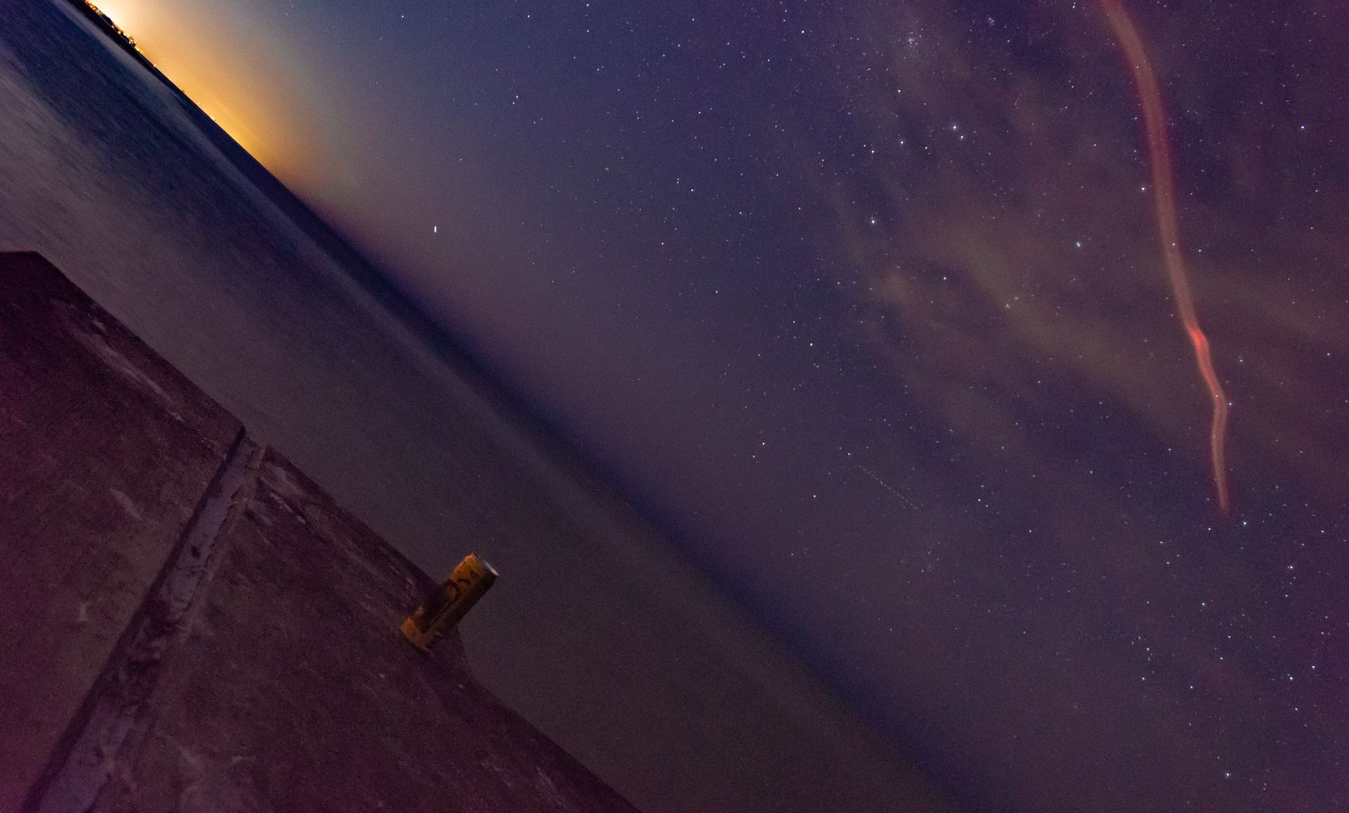 A starry night sky with a lighthouse in the foreground