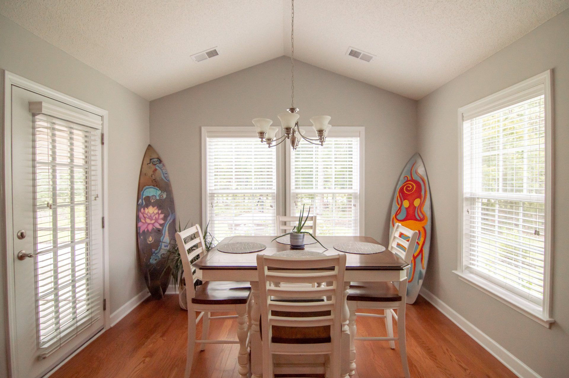 A dining room with a table and chairs and a surfboard on the wall.