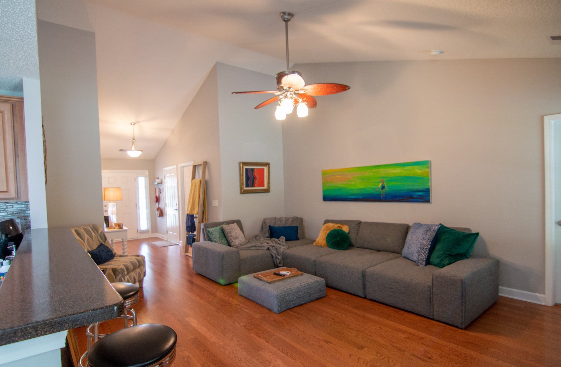 A living room with a large sectional couch and a ceiling fan.