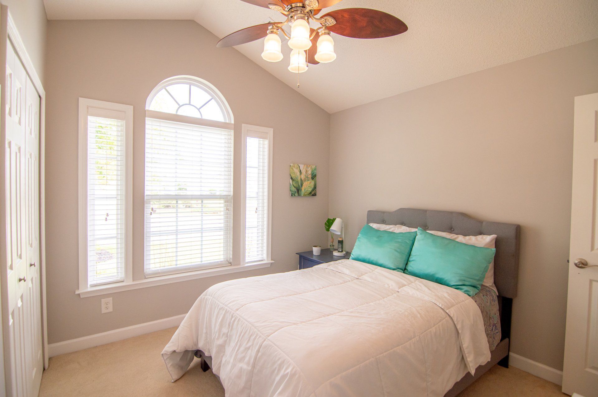 A bedroom with a bed and a ceiling fan.