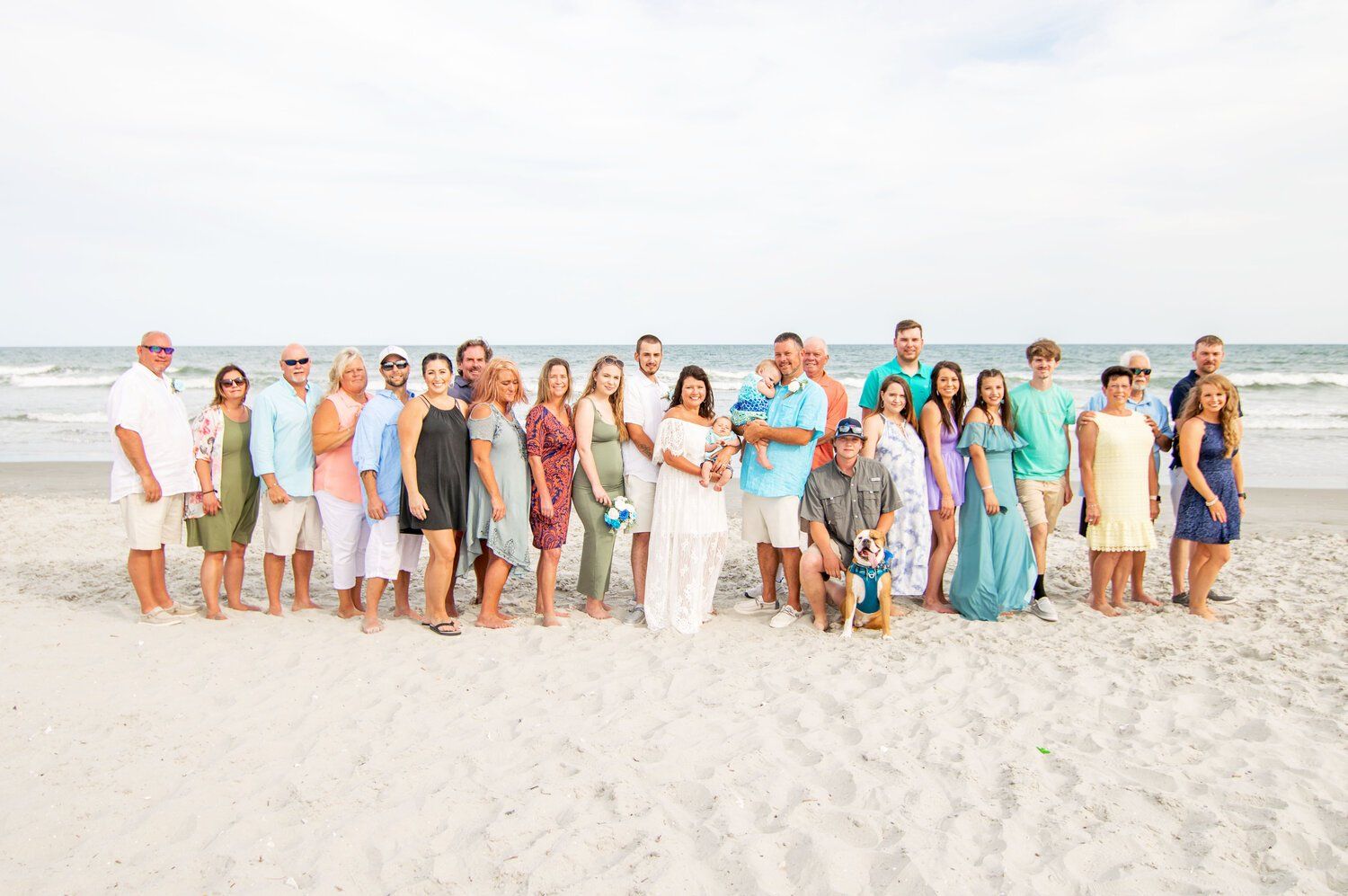 A large group of people are posing for a picture on the beach.