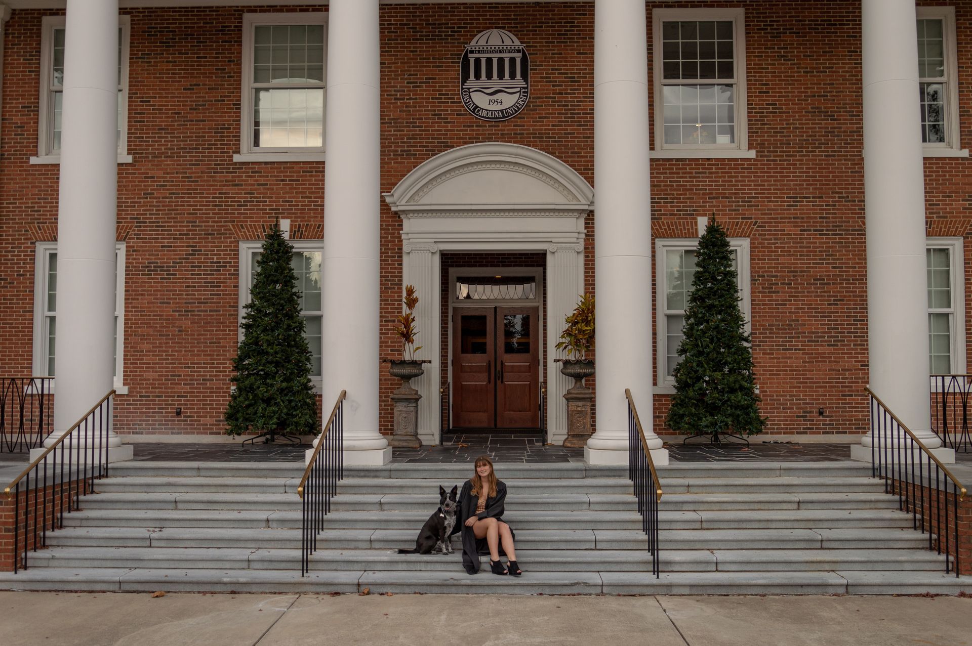 A woman sits on the steps of a large brick building