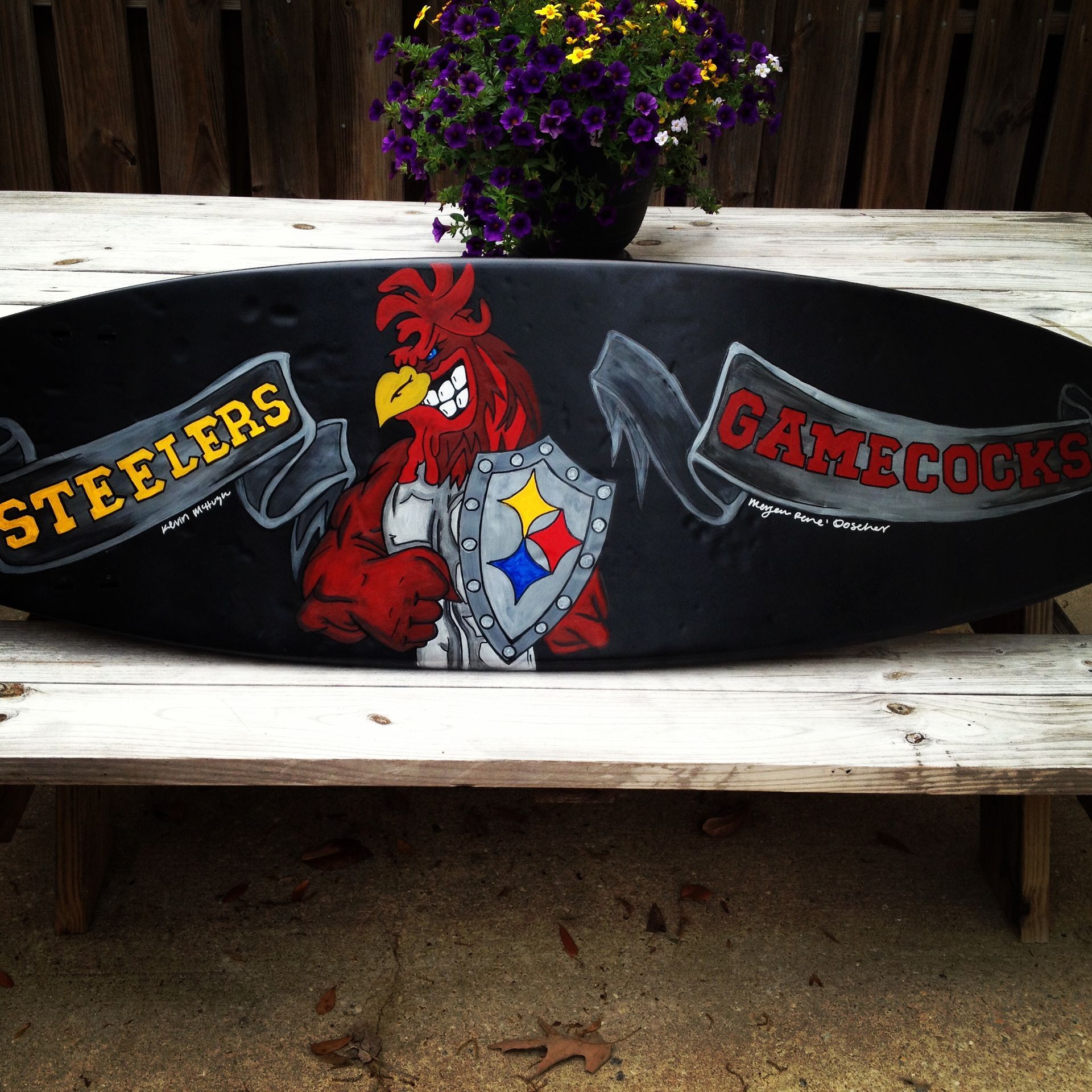 A skateboard with a rooster and the words steelers and gamecocks painted on it