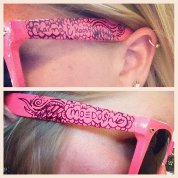 A woman wearing a pair of pink sunglasses with the word karma on them