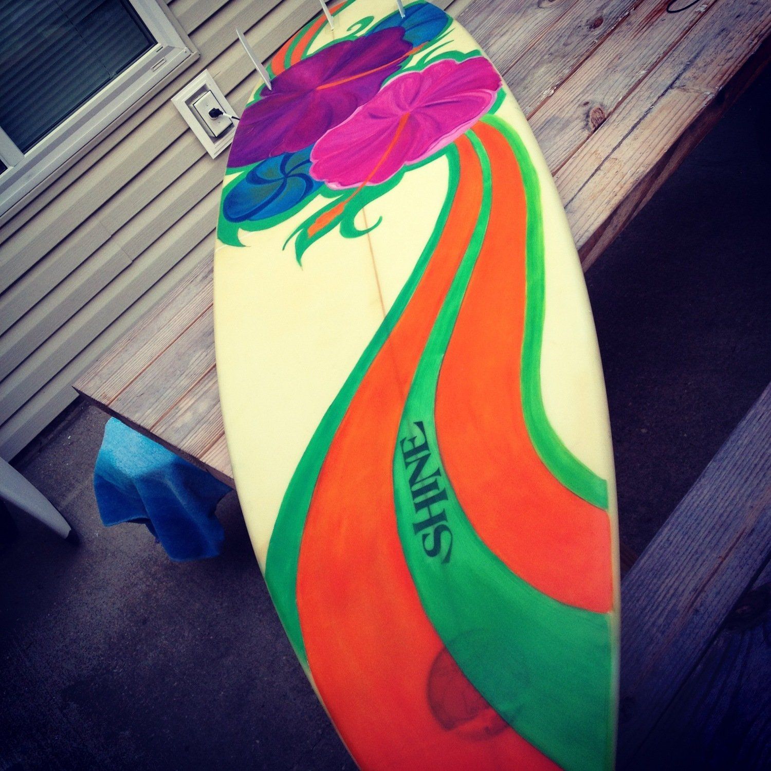 A colorful surfboard with the word shine on it
