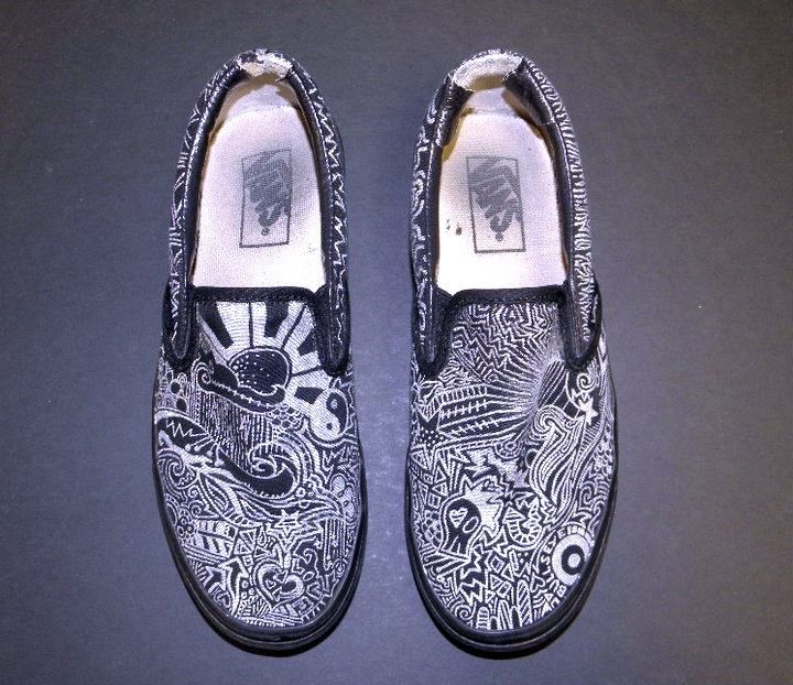 A pair of black and white vans shoes on a black surface