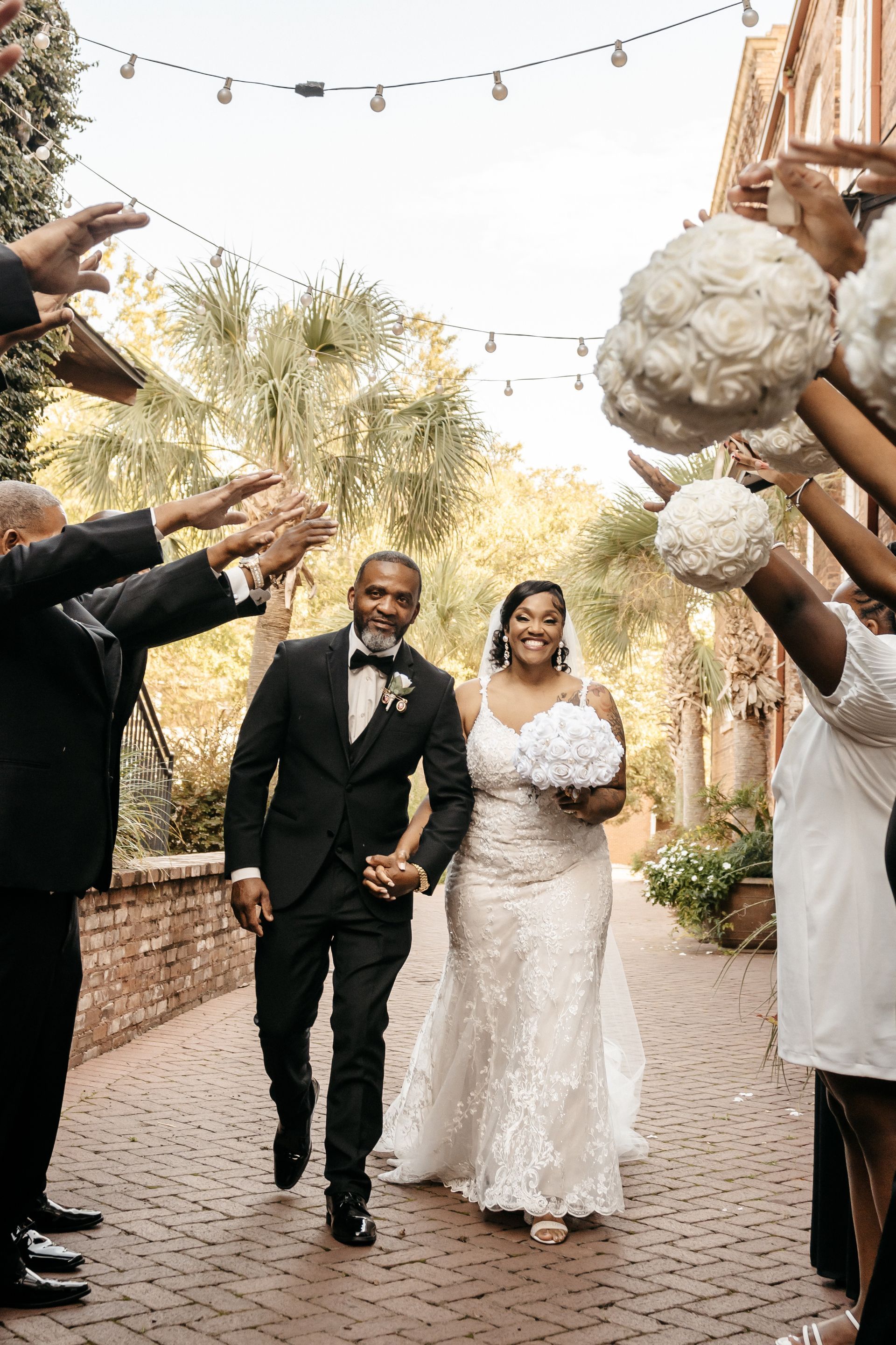 A bride and groom are standing next to each other in a park holding a bouquet of flowers.
