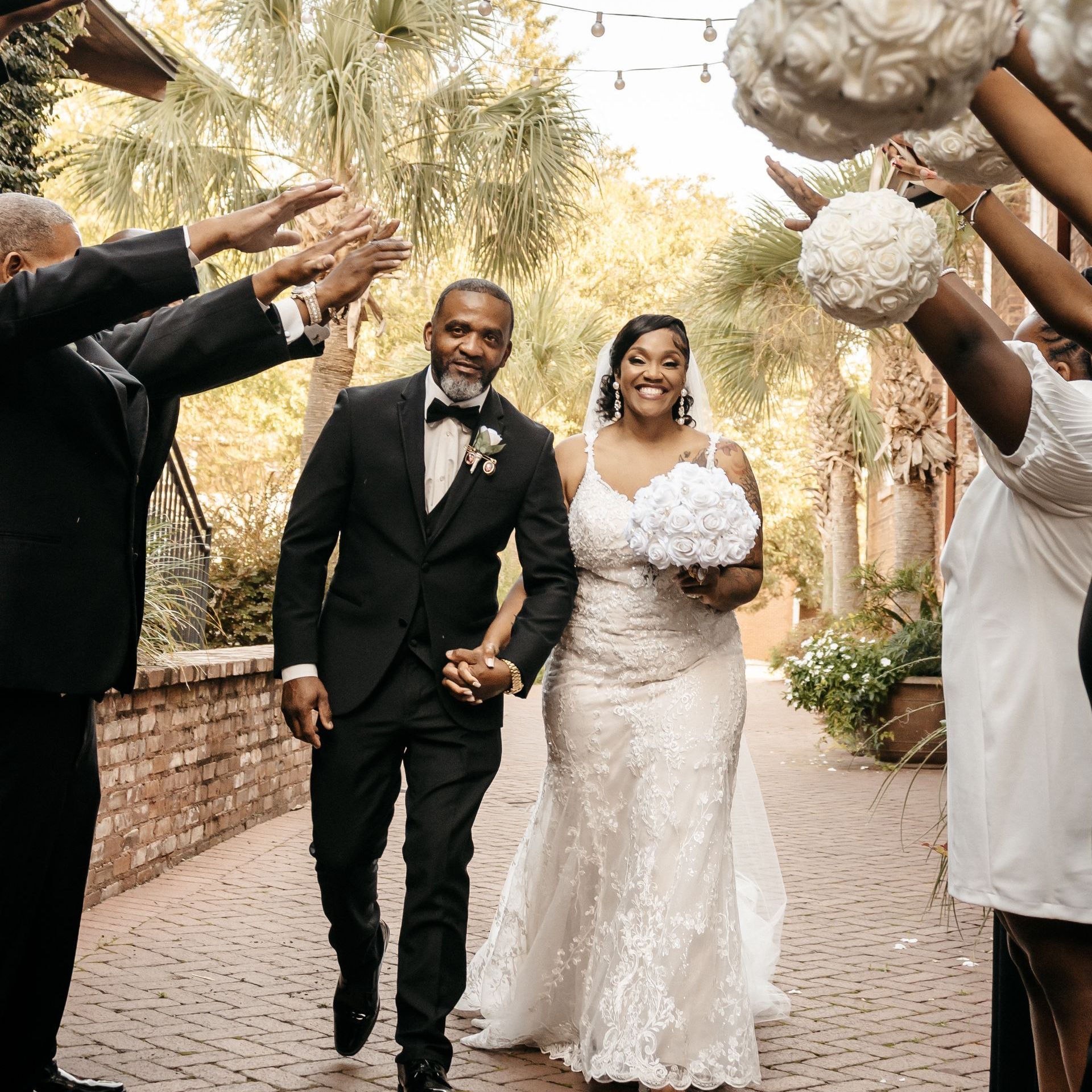 A bride and groom are standing next to each other in a park holding a bouquet of flowers.