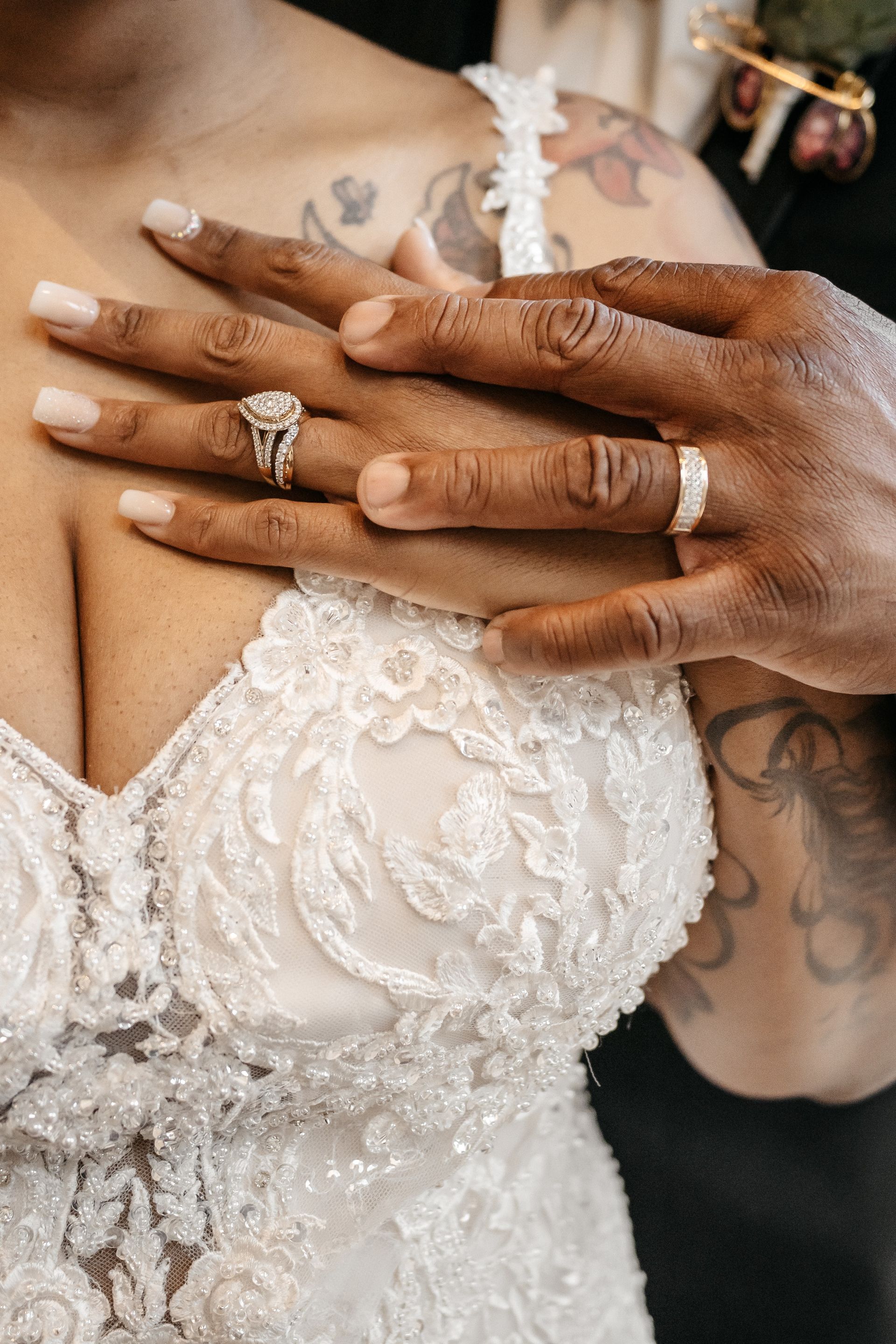 A bride and groom are showing off their wedding rings.