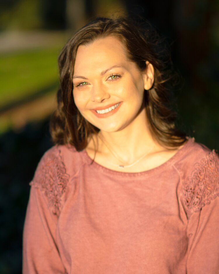 A woman in a pink sweater is smiling for the camera.