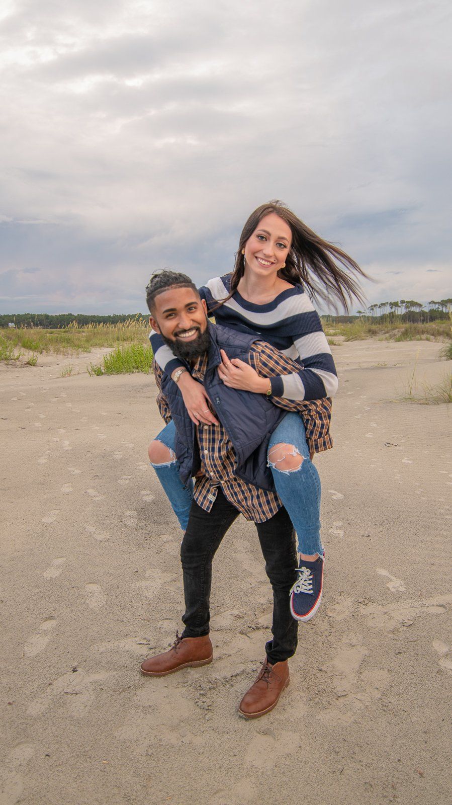 A man is carrying a woman on his back in a field.