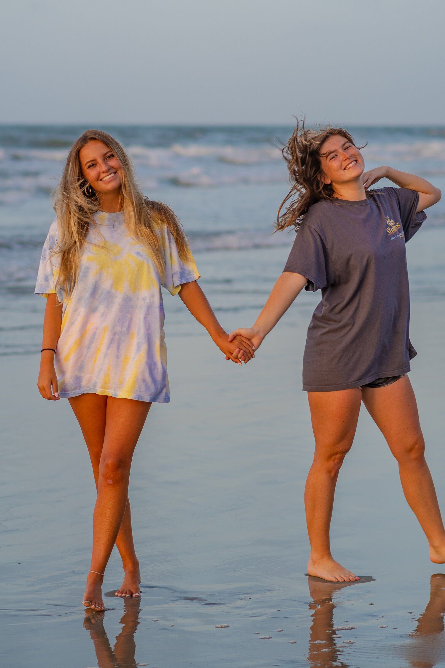 Two women are holding hands on the beach.