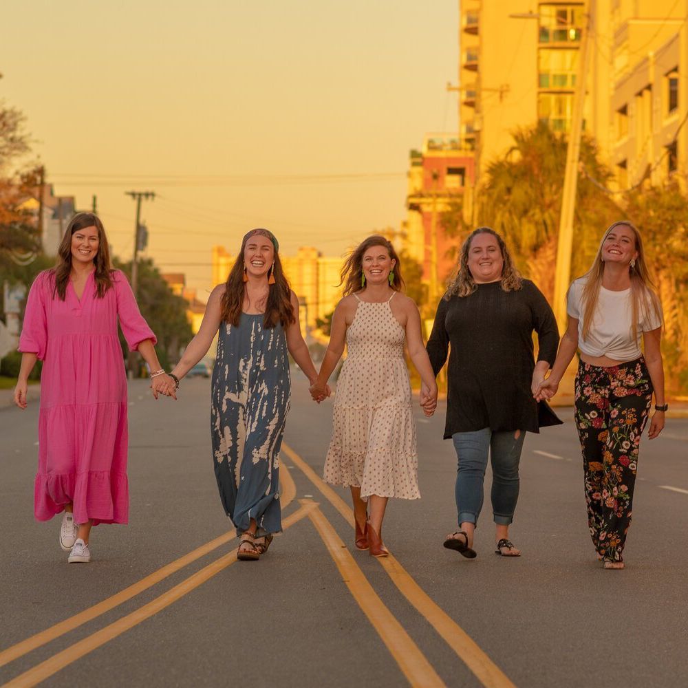 A group of women are walking down a street holding hands