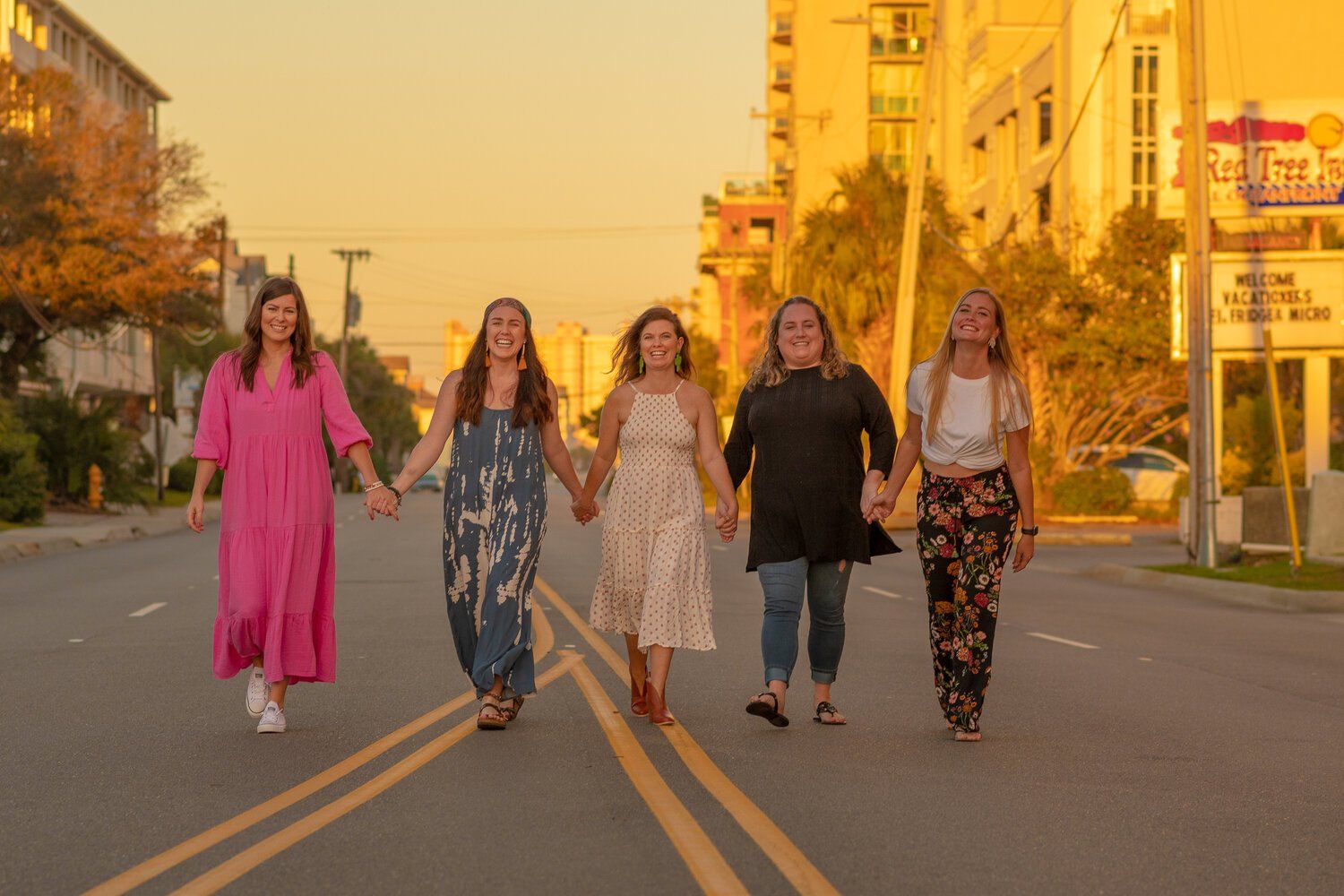 A group of women are walking down a street holding hands.