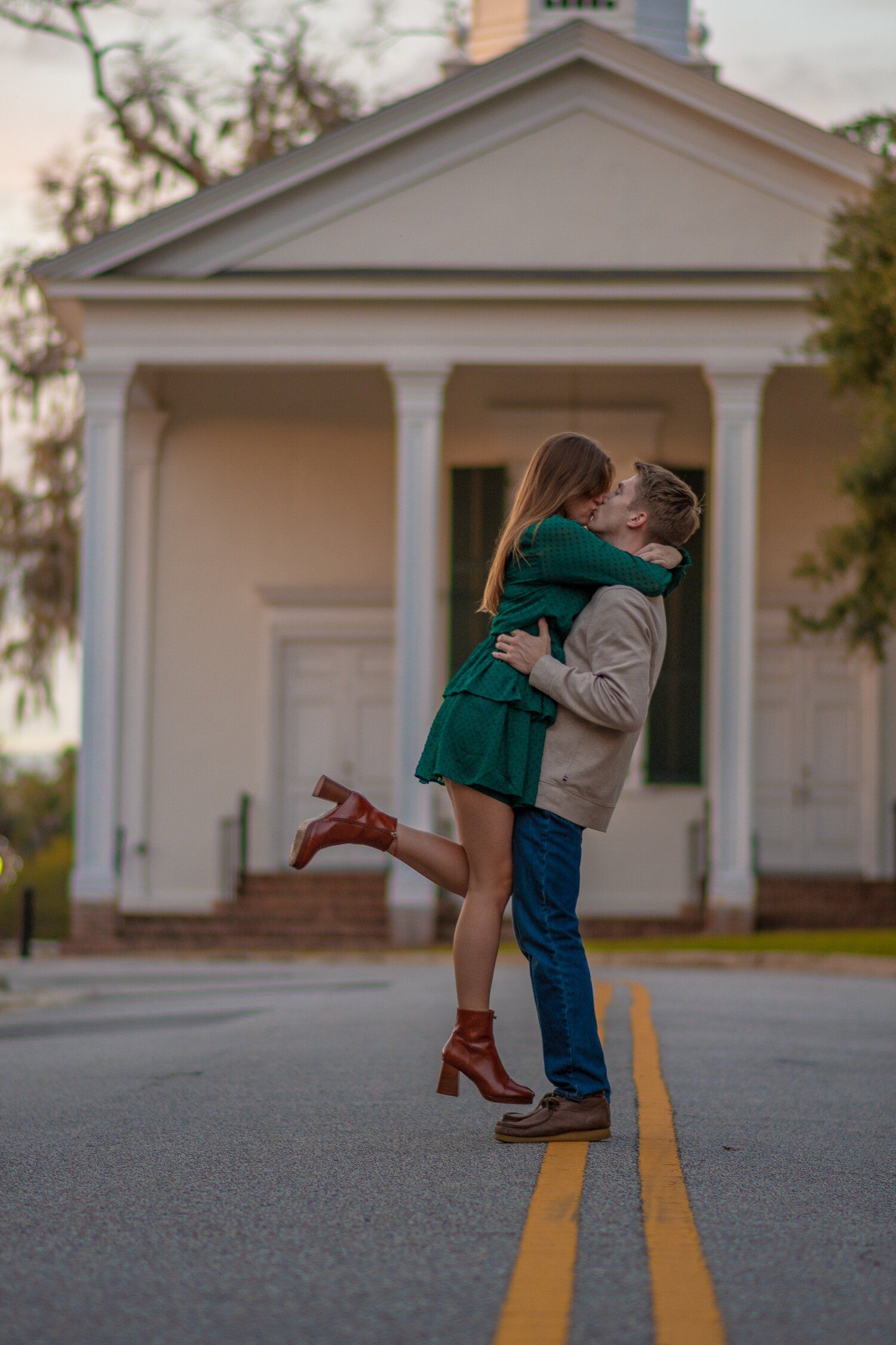 A man is holding a woman in his arms and kissing her in front of a church.