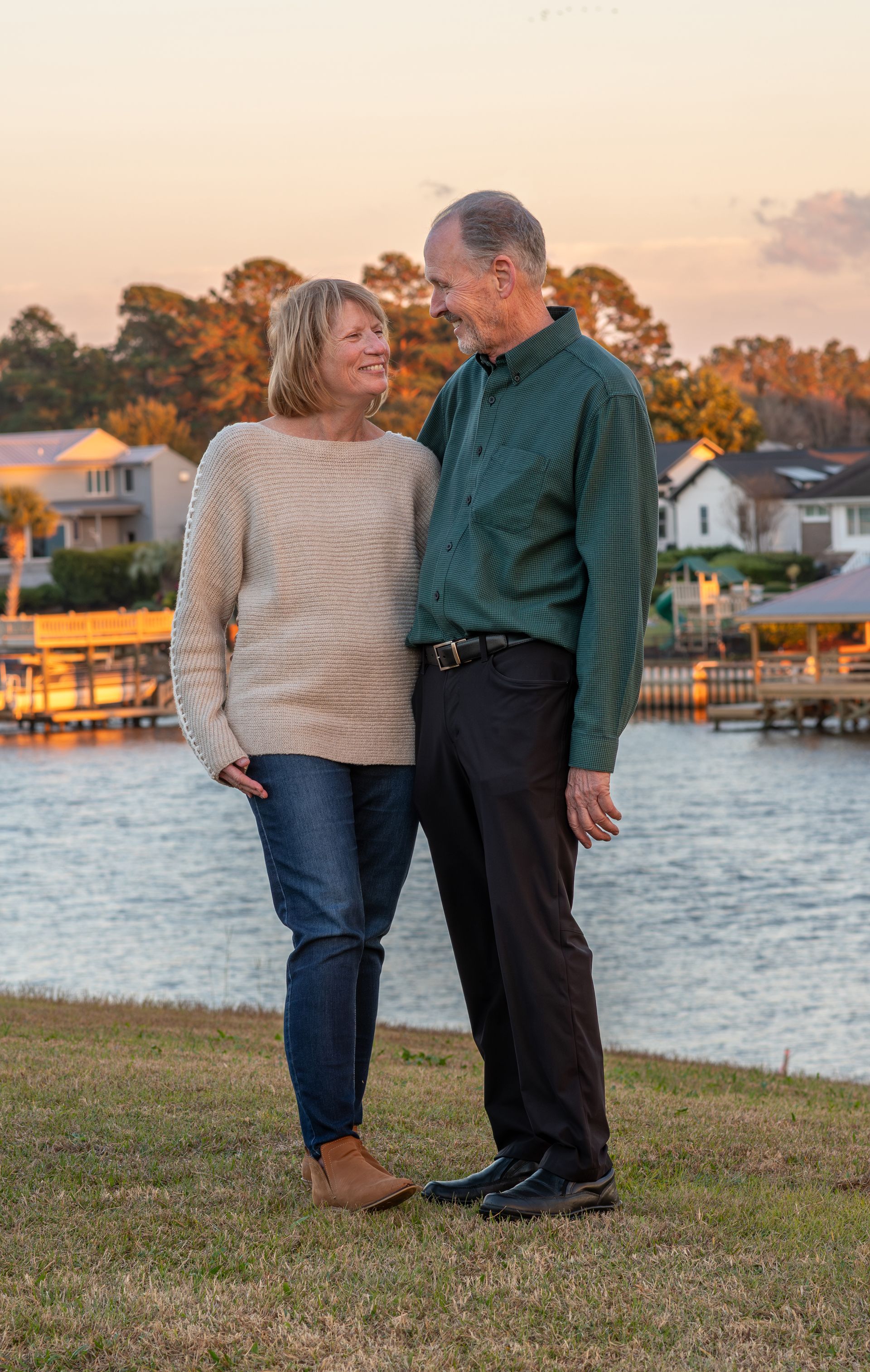 A man and a woman are standing next to each other in front of a body of water.