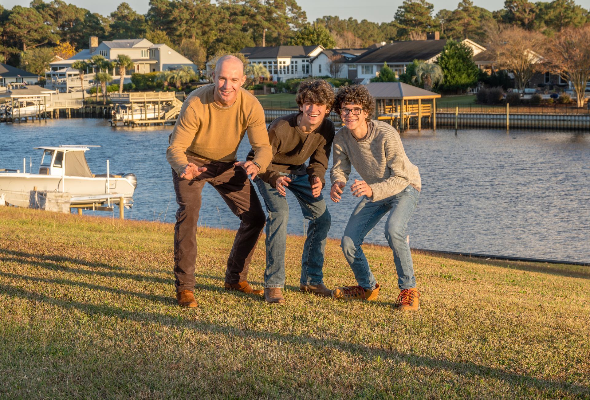Three people are posing for a picture in front of a body of water.