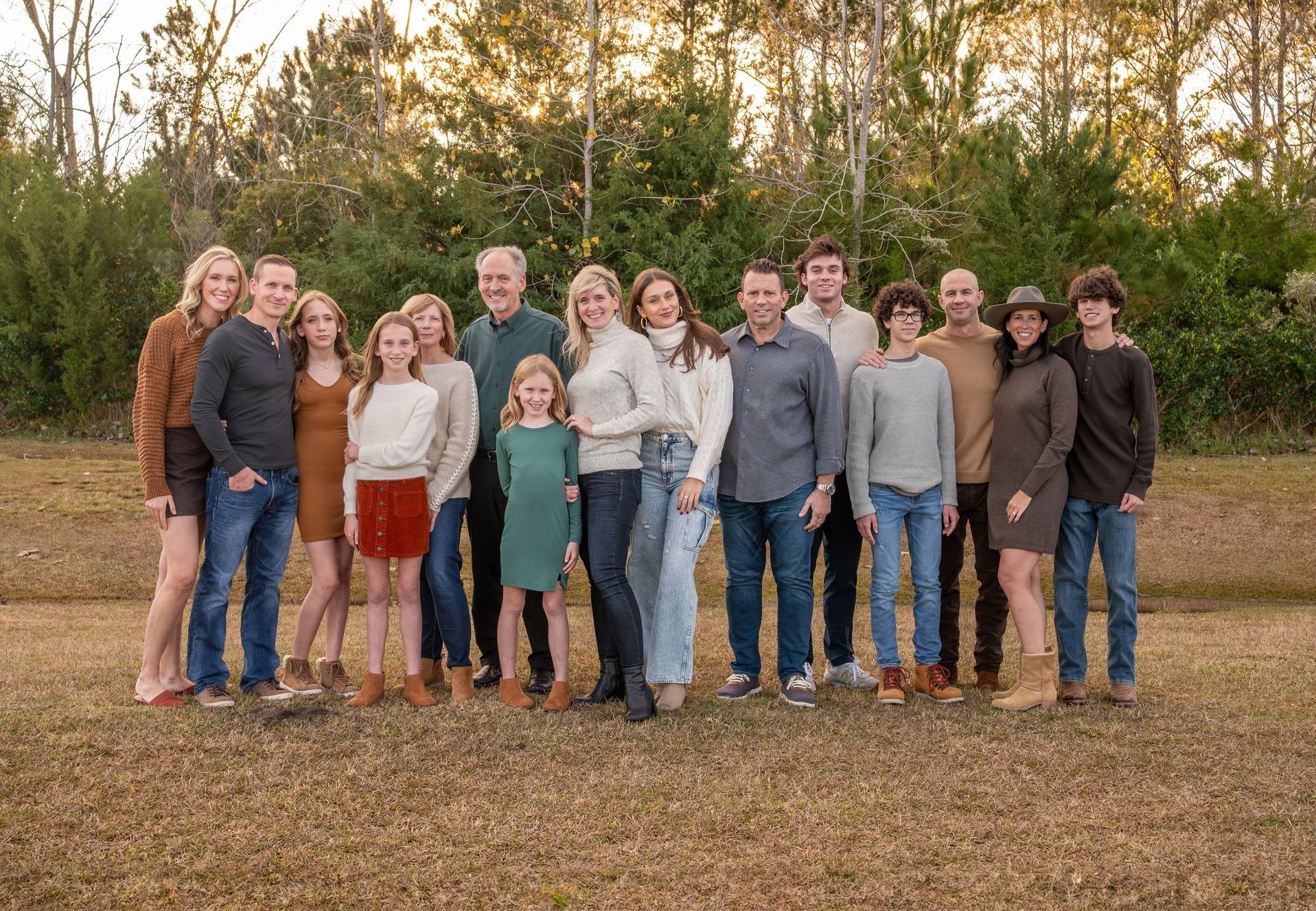 A large family is posing for a picture on the beach.