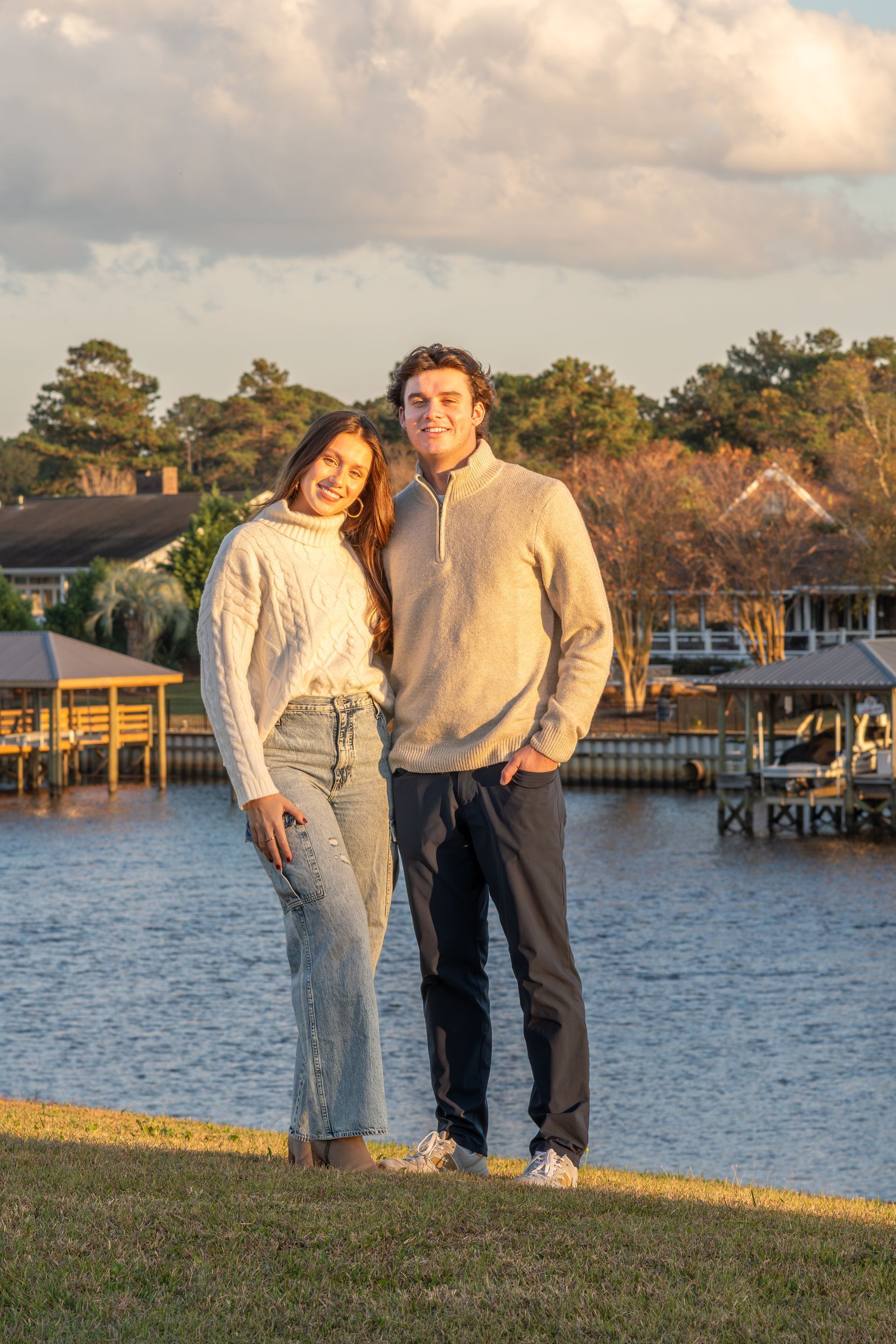 A man and a woman are standing next to each other in front of a body of water.
