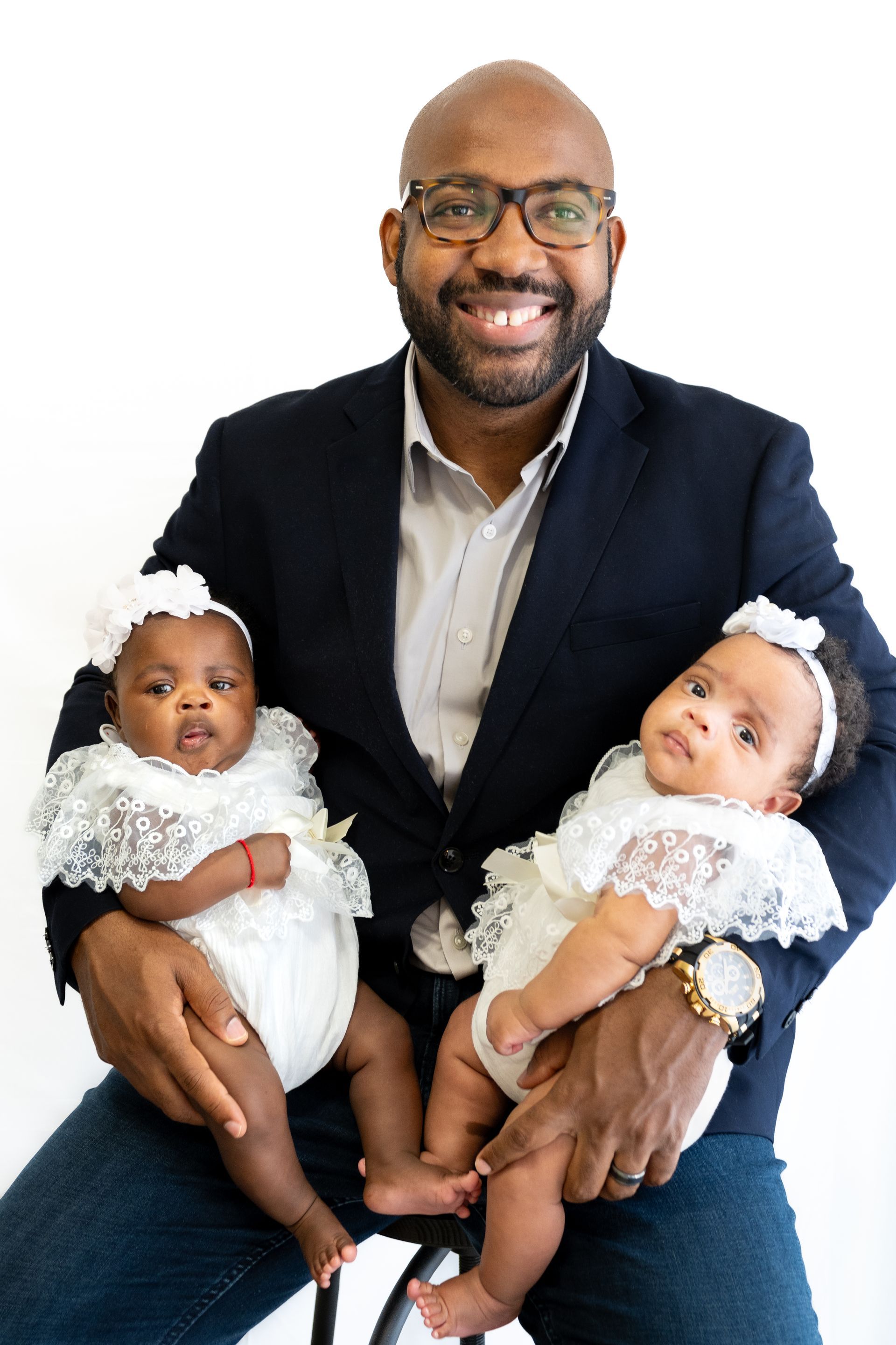A man in a suit is holding two babies in his arms.