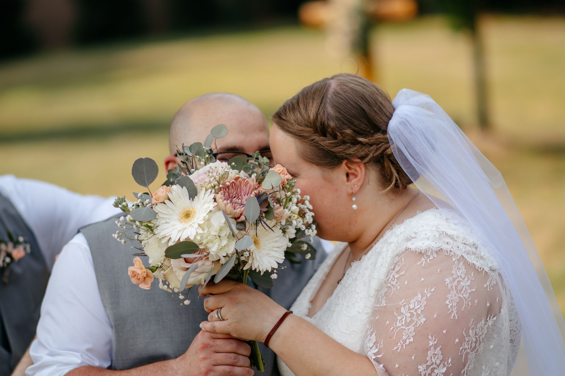A bride and groom kissing while the bride holds a bouquet of flowers.