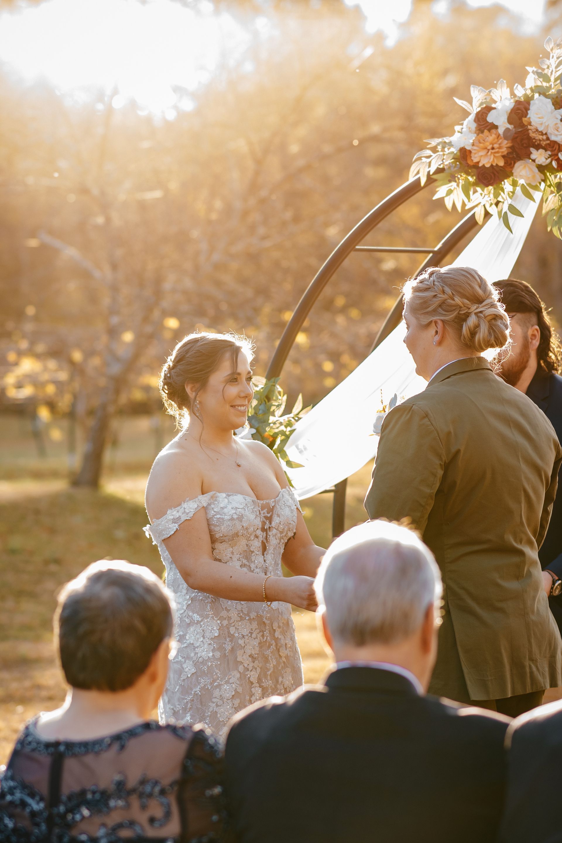 A bride and groom are holding hands during their wedding ceremony.