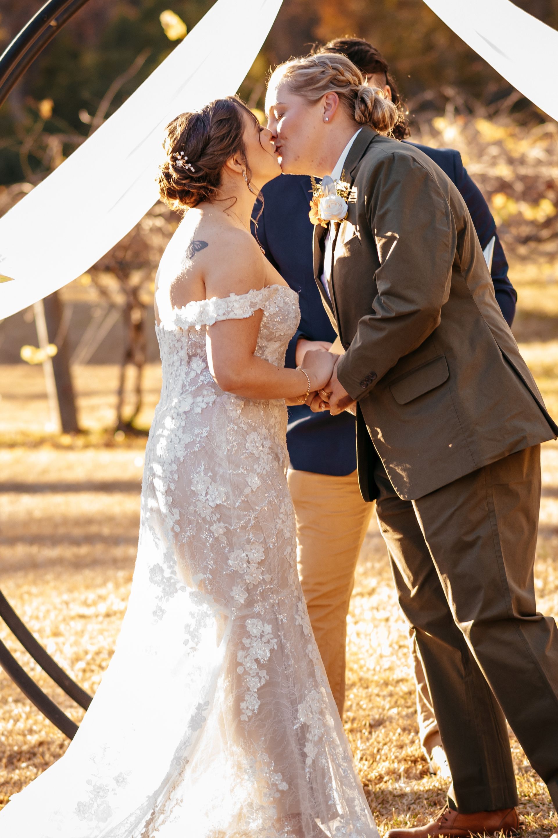 A bride and groom are kissing at their wedding ceremony.