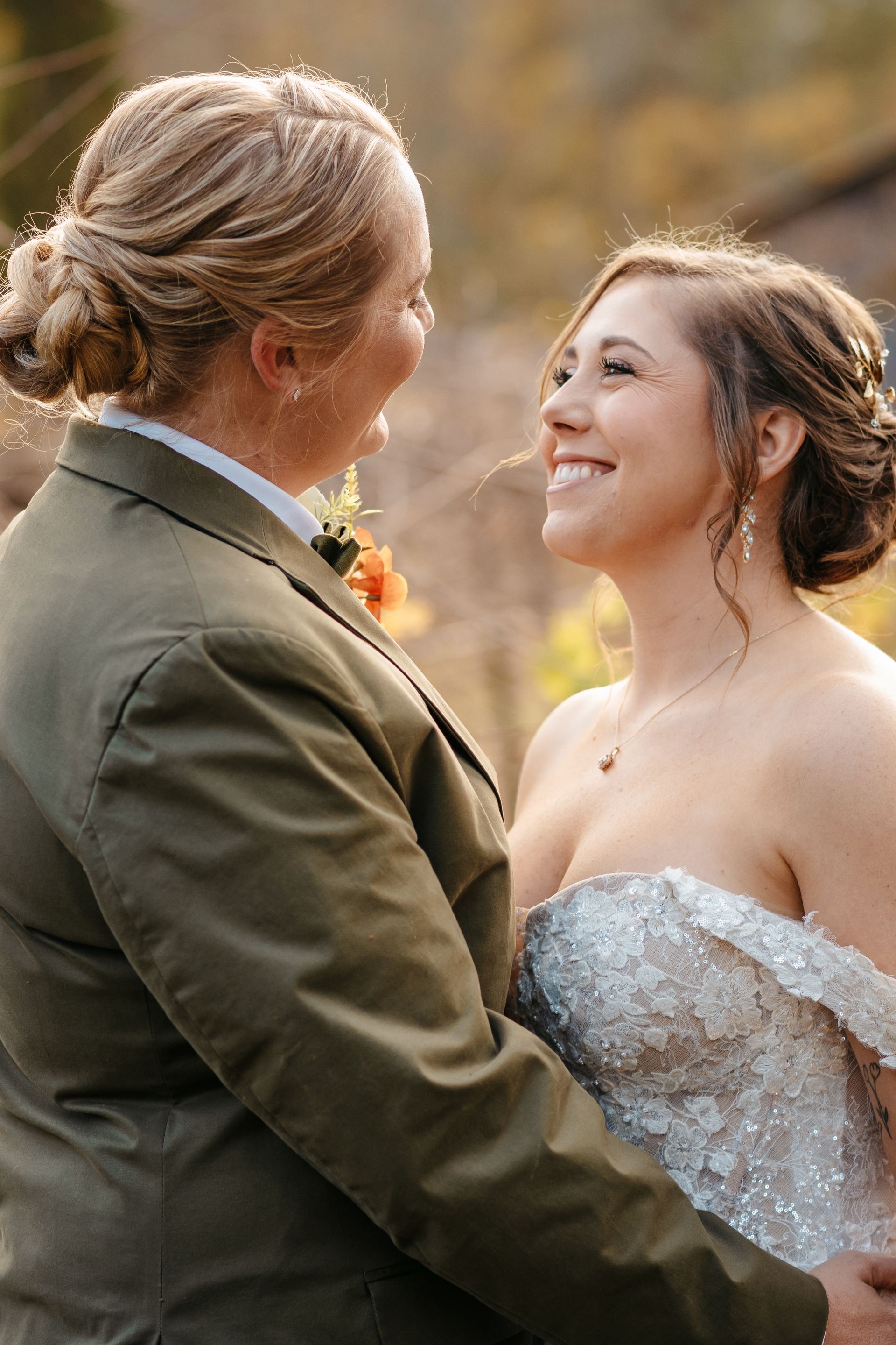 A bride and groom are looking at each other and smiling.