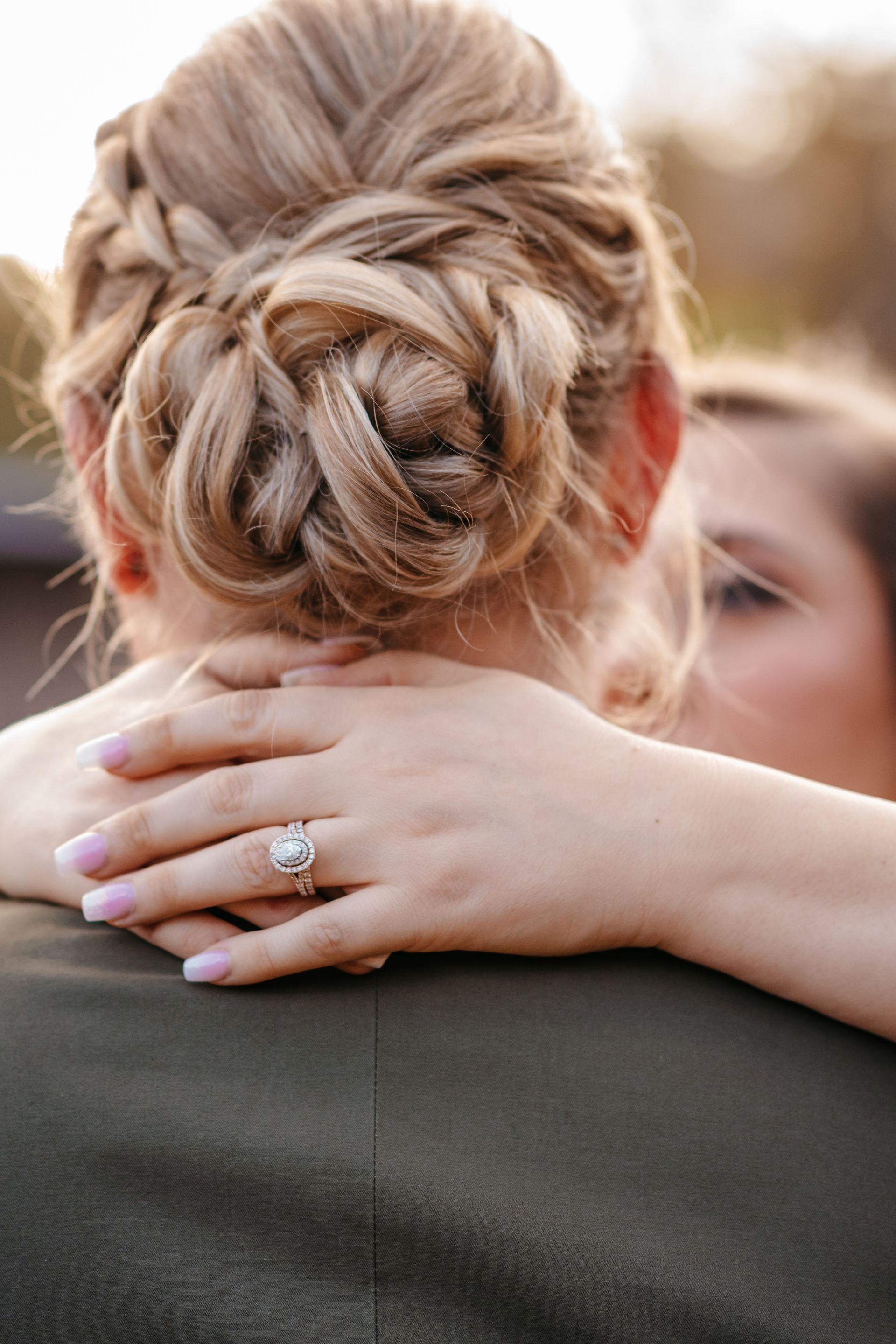 A woman with a ring on her finger is hugging a man.