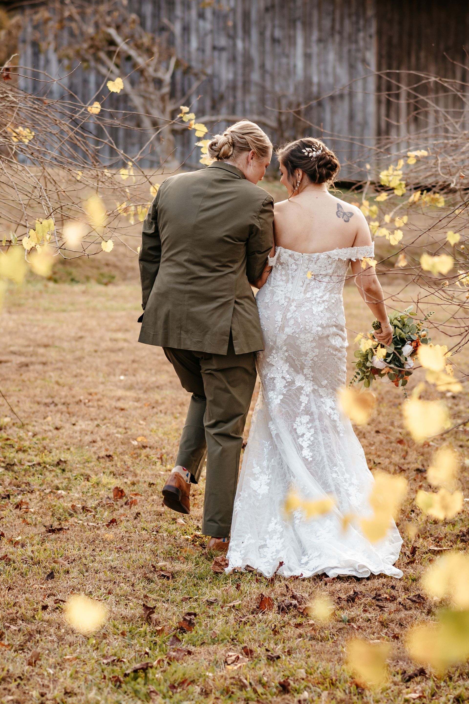 A bride and groom are walking through a field.