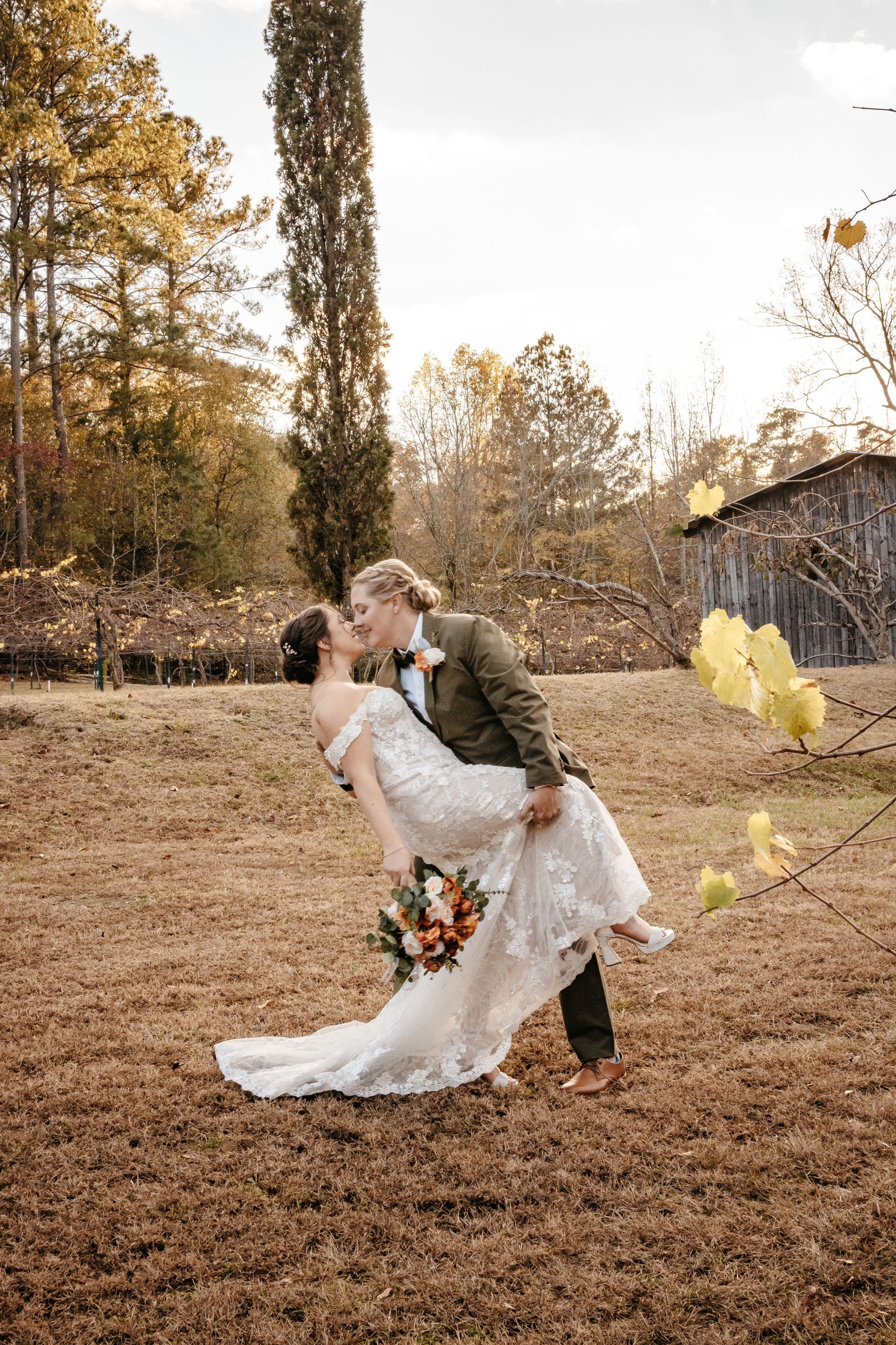 A bride and groom are kissing in a field.