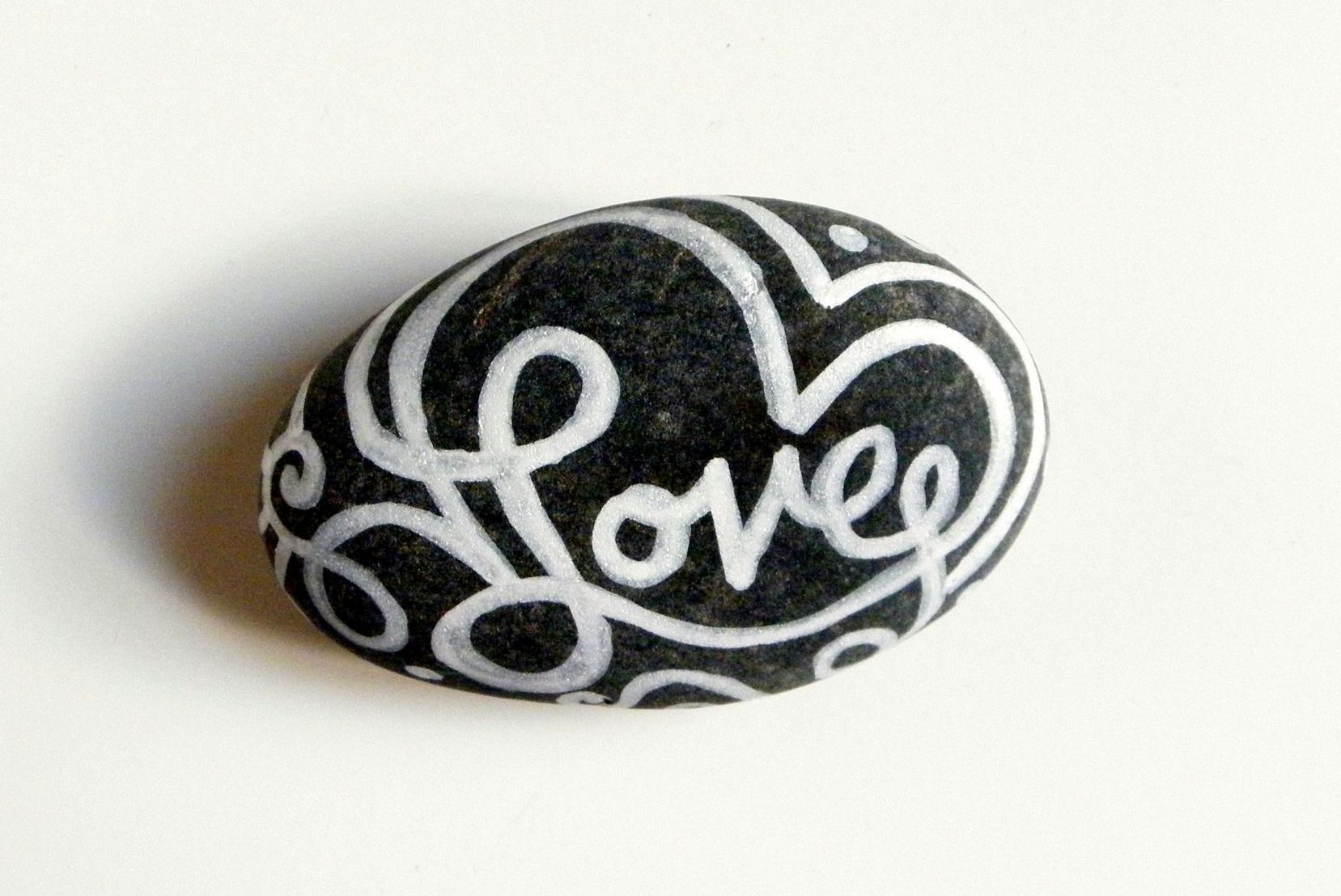 A black and white rock with the word love painted on it