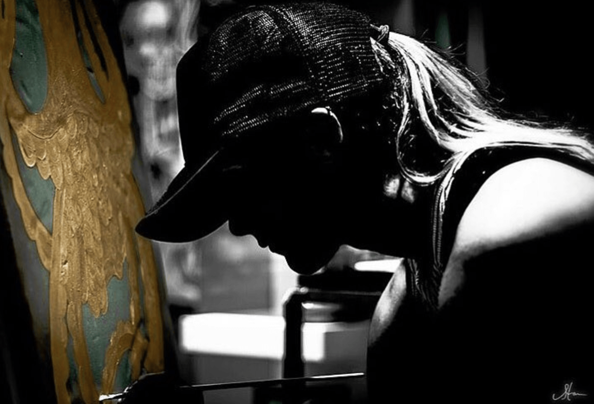 A black and white photo of a woman , Morgan René Doscher painting on a surfboard of an octopus.