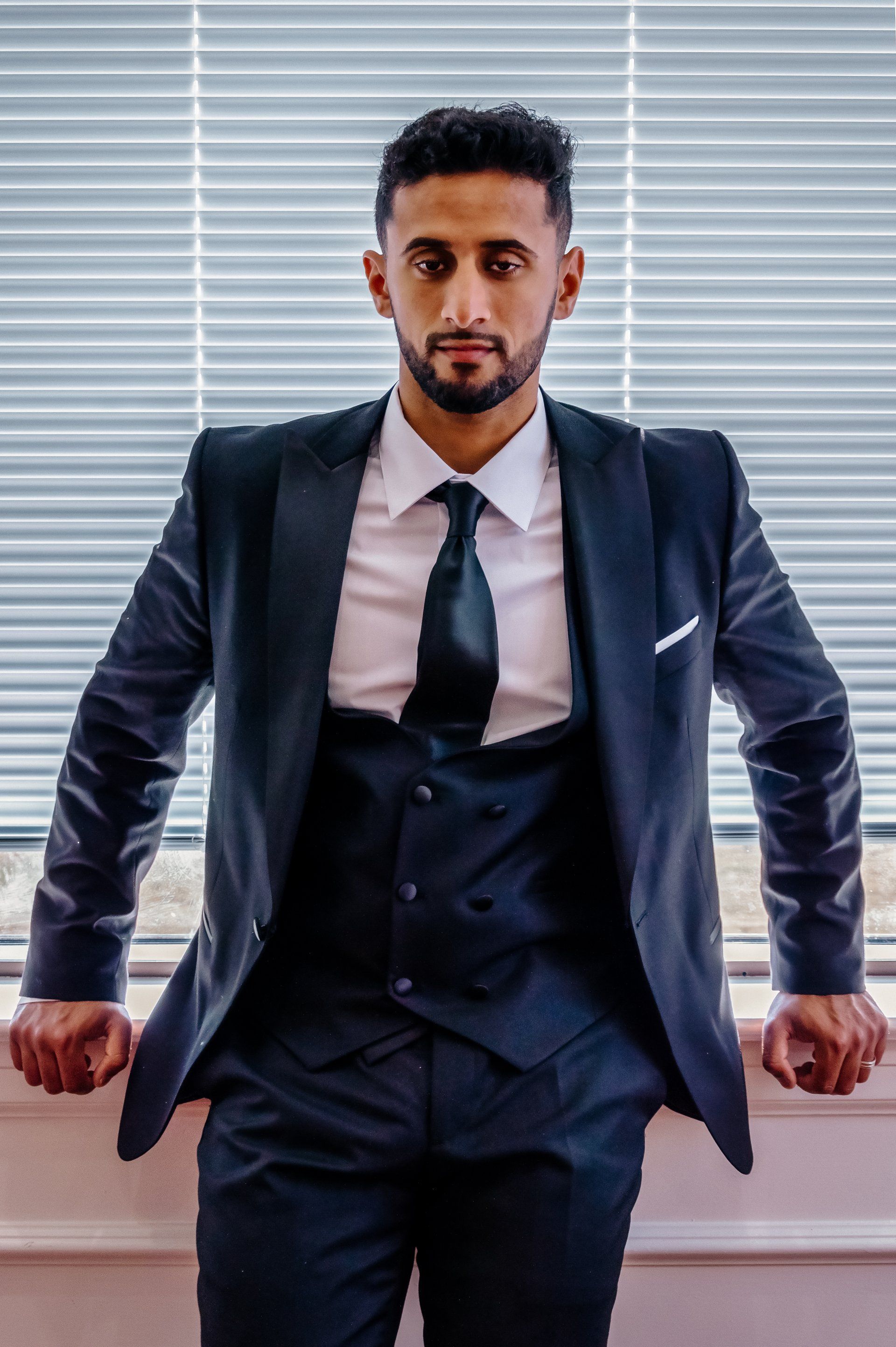 A man in a suit and tie is leaning against a window.