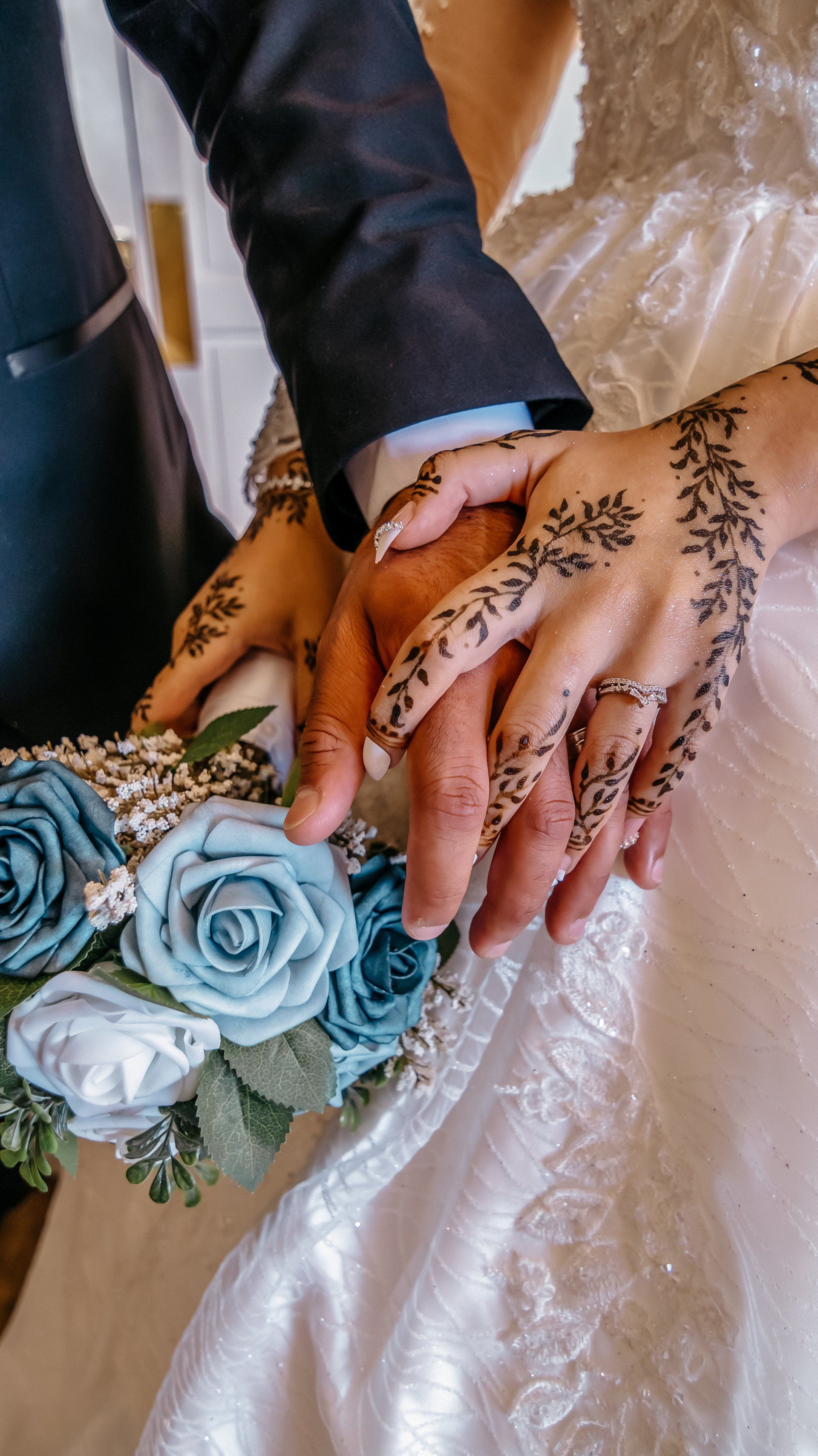 A bride and groom are holding hands with henna on their hands.