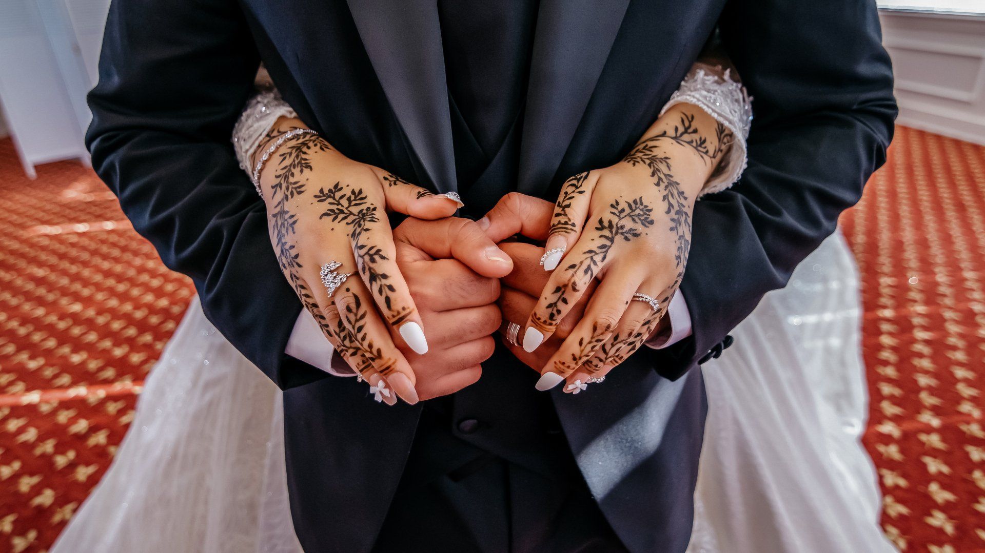 A bride and groom are holding hands with henna on their hands.
