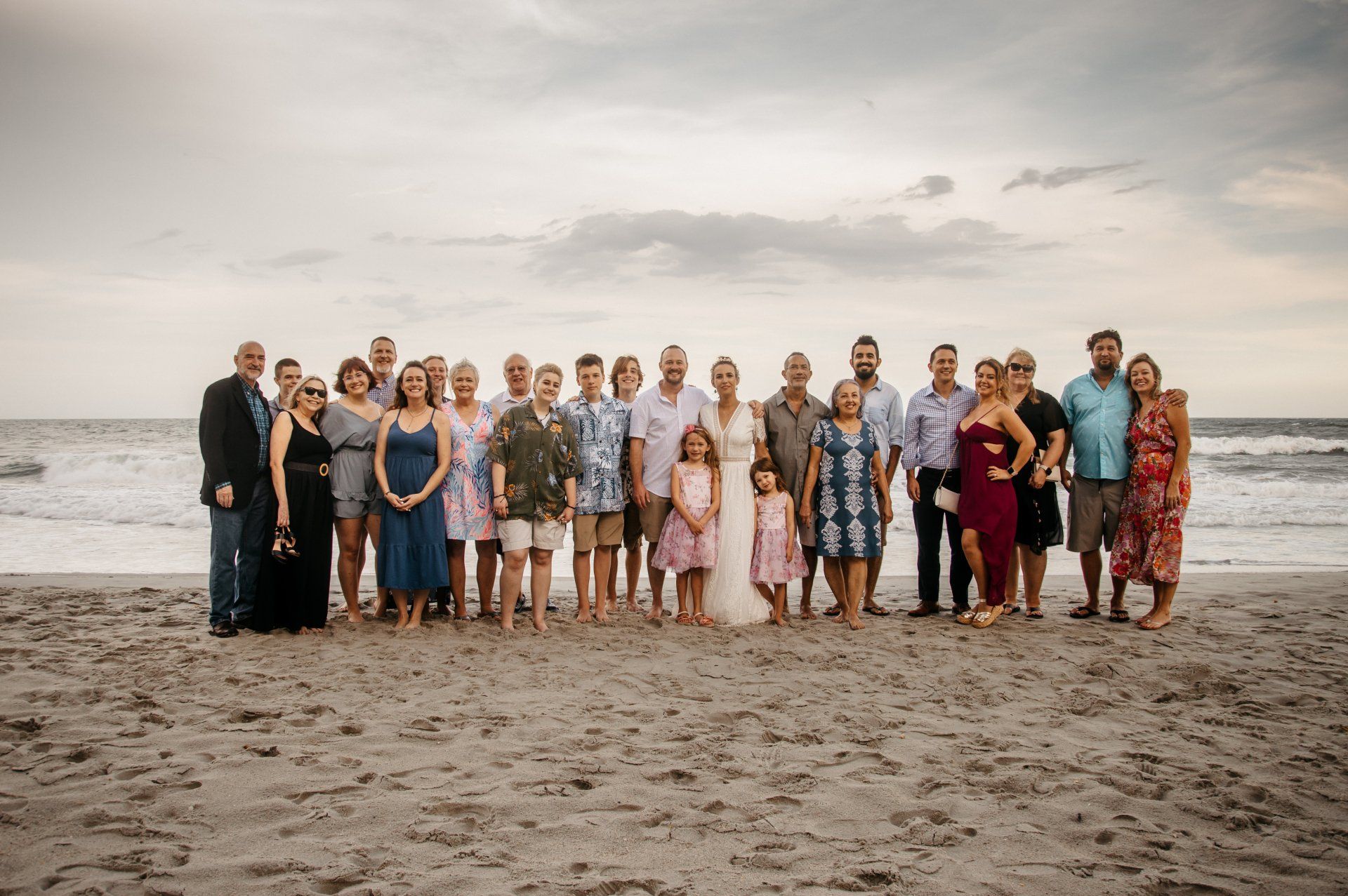 A large group of people are posing for a picture on the beach.