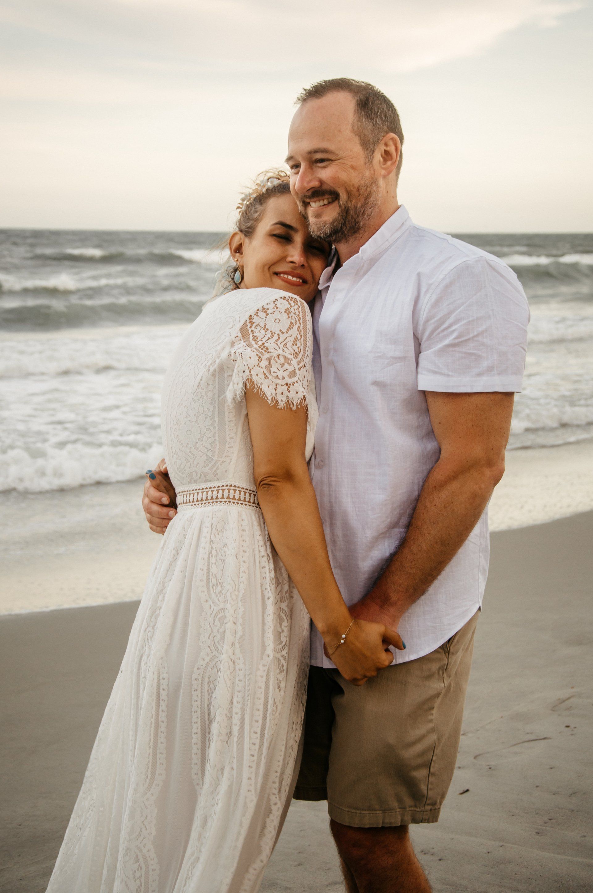 A man and a woman are posing for a picture on the beach.
