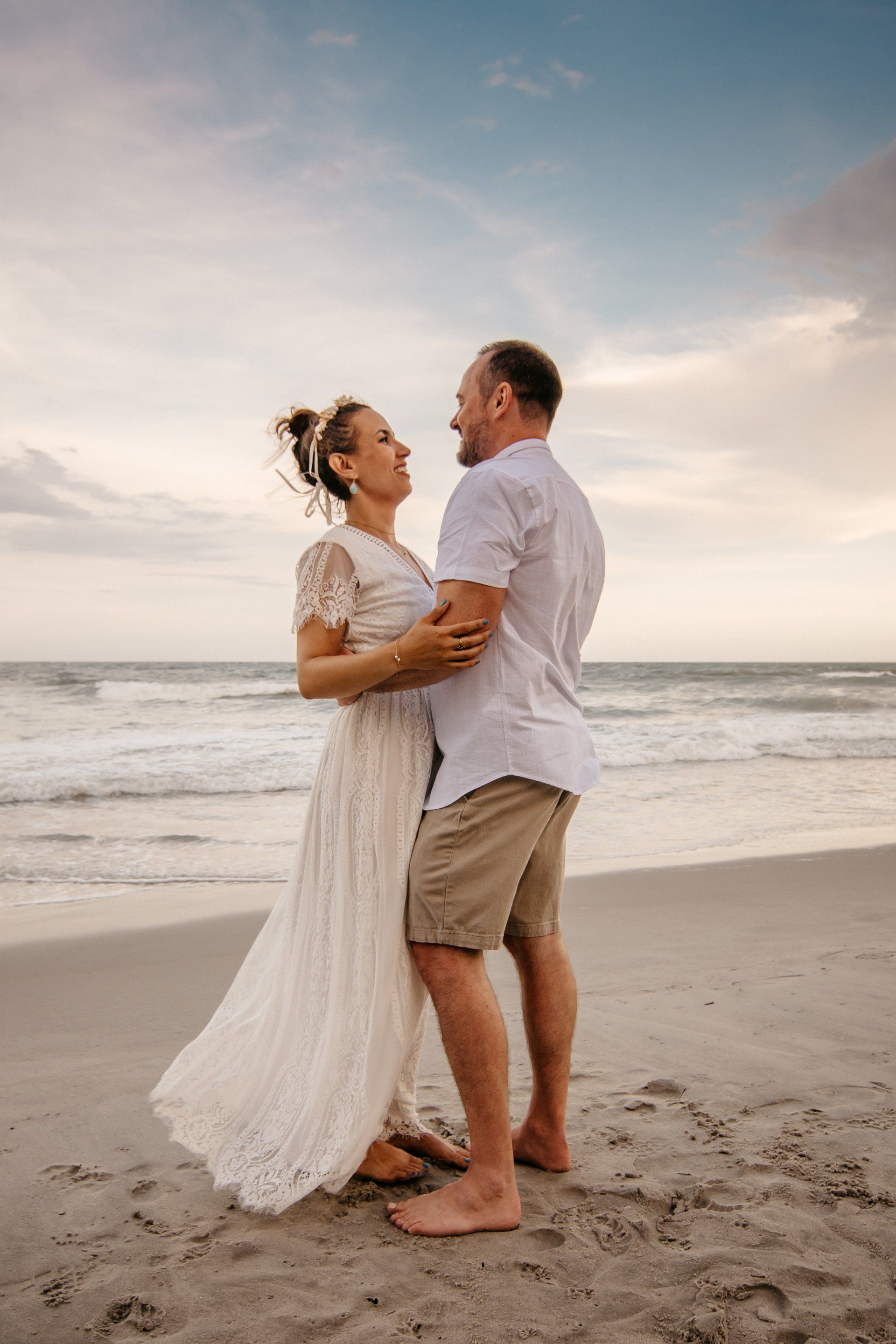 A man and a woman are standing on a beach looking at each other.
